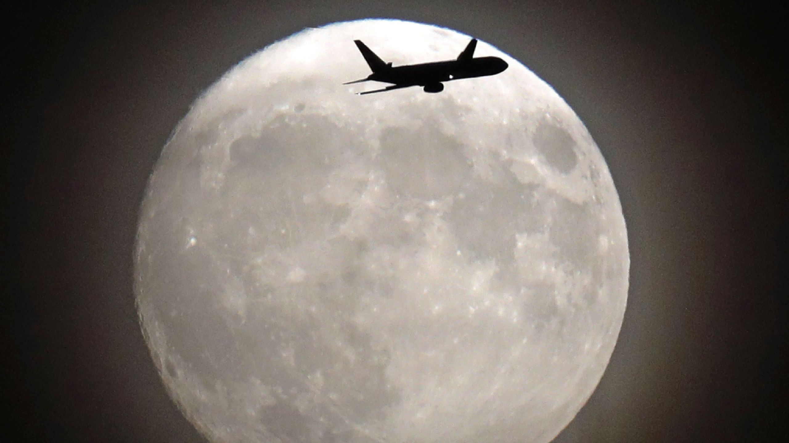 A commercial jet flies in front of the moon on its approach to Heathrow airport in west London on November 13, 2016. (Credit: ADRIAN DENNIS/AFP/Getty Images)