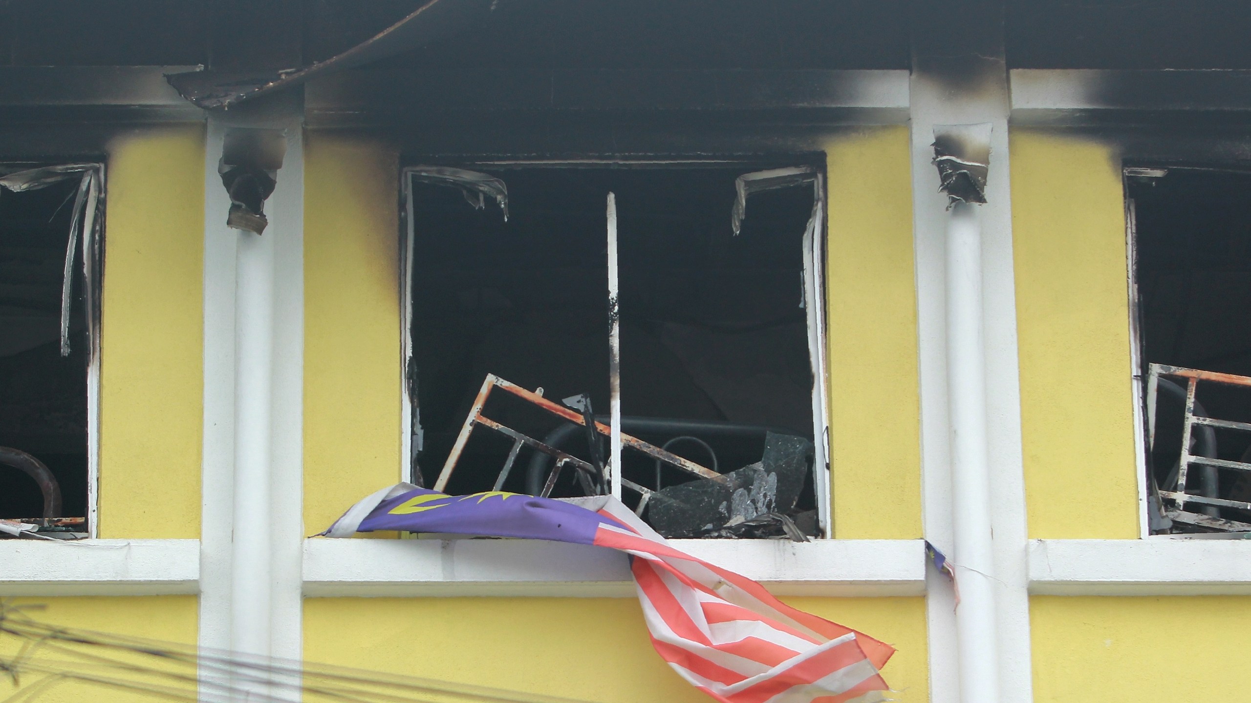 Malaysian national flag flutters outside burnt windows of the Darul Quran Ittifaqiyah religious school in Kuala Lumpur on Sept. 14, 2017. (Credit: Sadiq Asyraf / AFP / Getty Images)