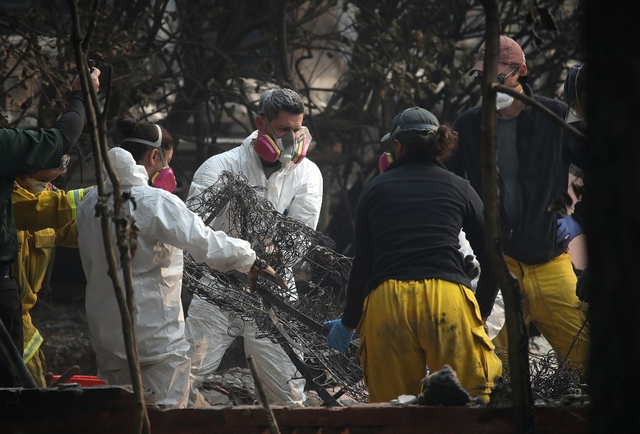 Rescue workers shake a burned mattress as they search for bone fragments while collecting human remains from a home destroyed by the Camp Fire on Nov. 16, 2018 in Paradise, California. (Credit: Justin Sullivan/Getty Images)