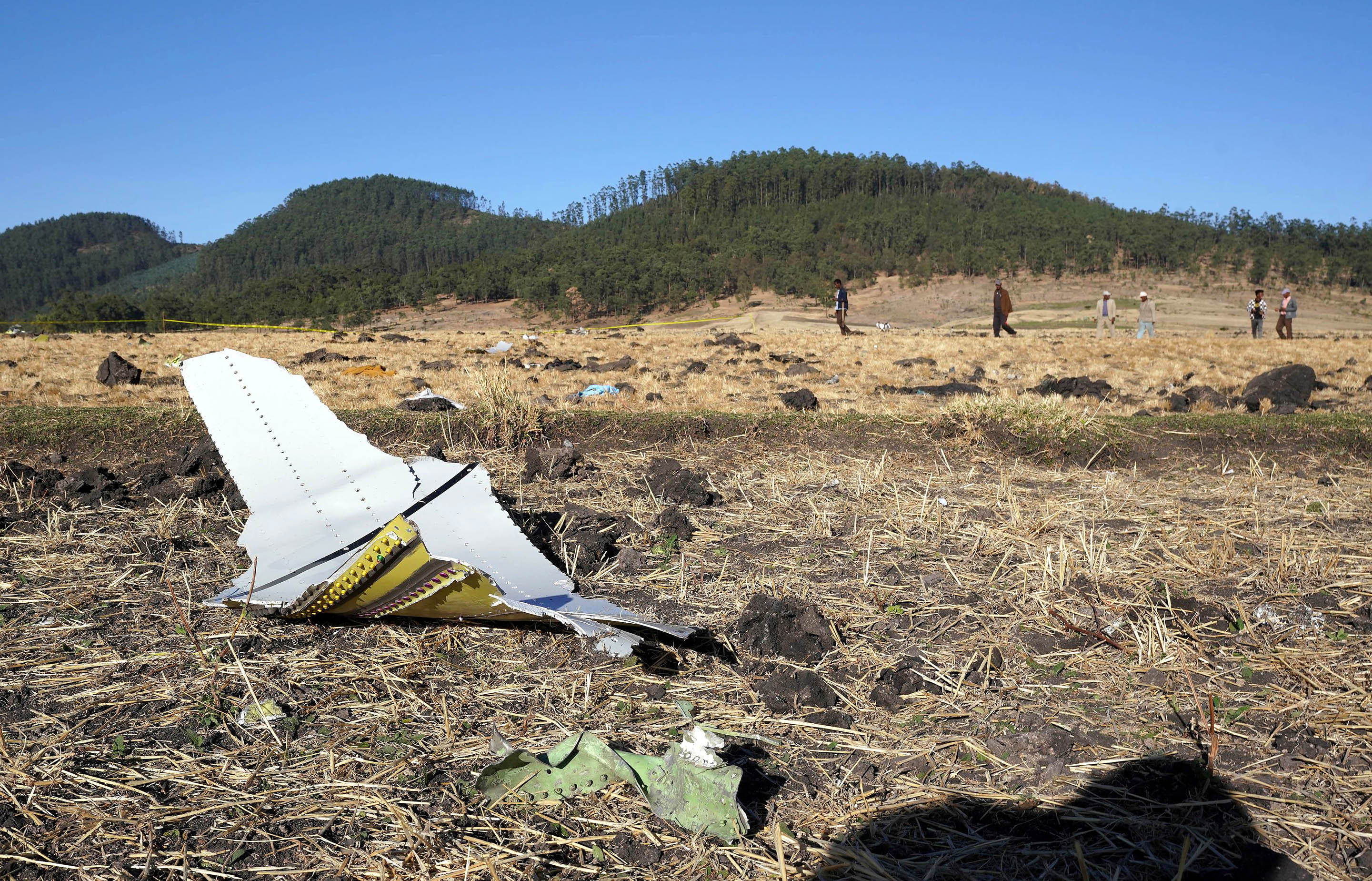 A piece of the fuselage of ET Flight 302 can be seen in the foreground as local residents collect debris at the scene where Ethiopian Airlines Flight 302 crashed in a wheat field on March 10, 2019, in Addis Ababa, Ethiopia. (Credit: Jemal Countess/Getty Images)