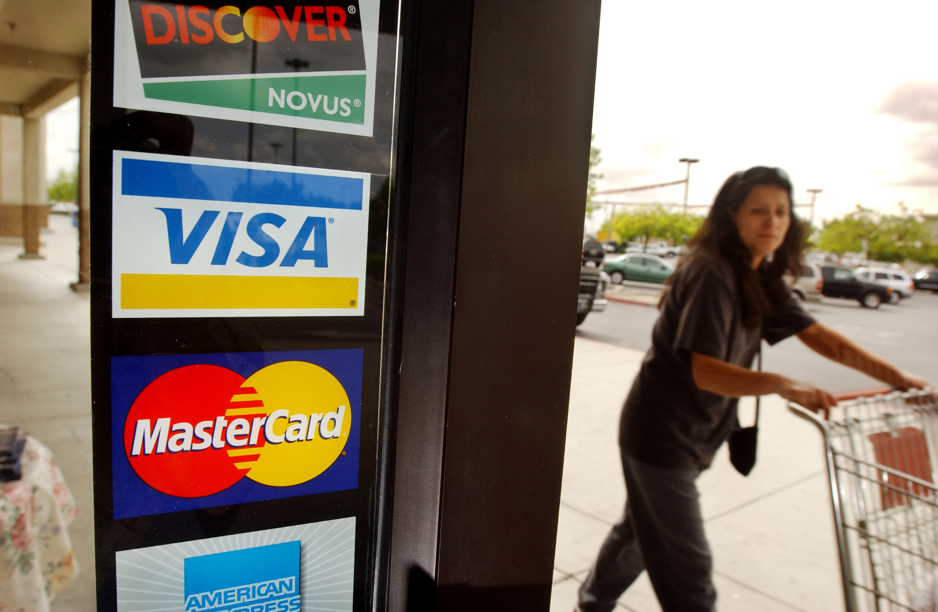A shopper passes a shop door advertising acceptance of purchases with Master Card, Visa, and other credit cards in Bakersfield on April 29, 2003. (Credit: David McNew/Getty Images)