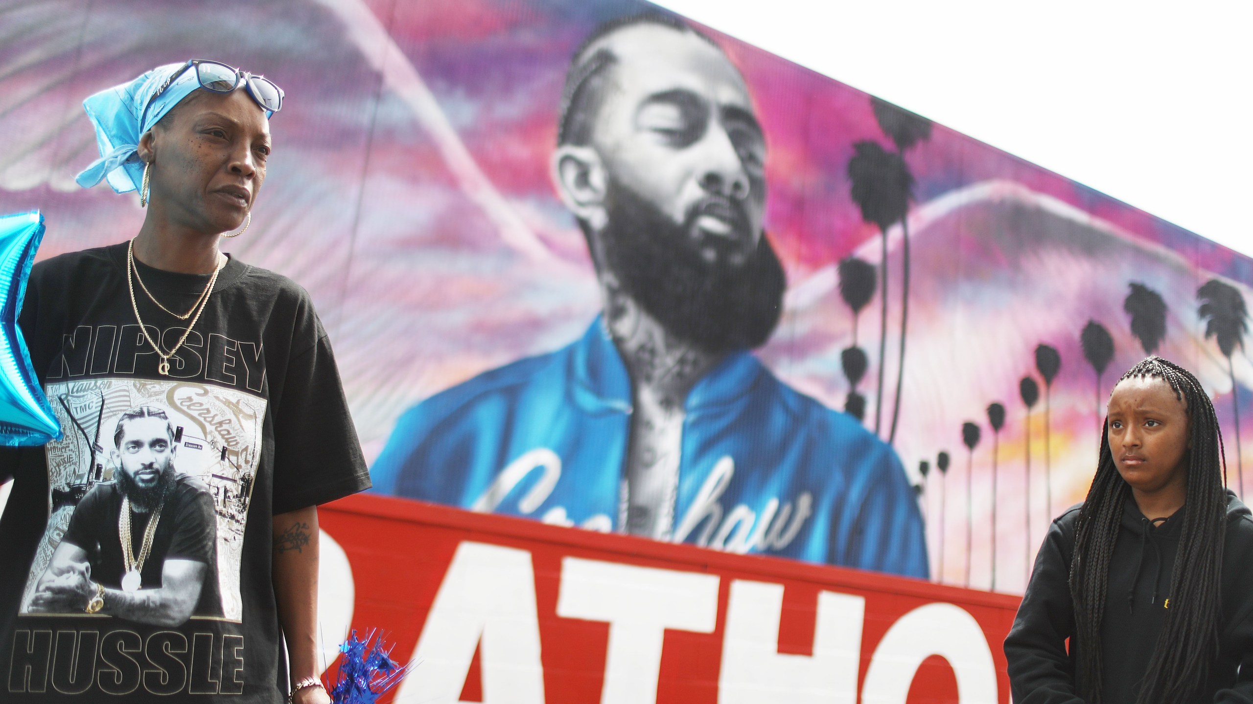 Fans gather in front of a mural to slain rapper Nipsey Hussle as they await outside The Marathon Clothing store for his funeral procession in South Los Angeles on April 11, 2019. (Credit: Mario Tama / Getty Images)