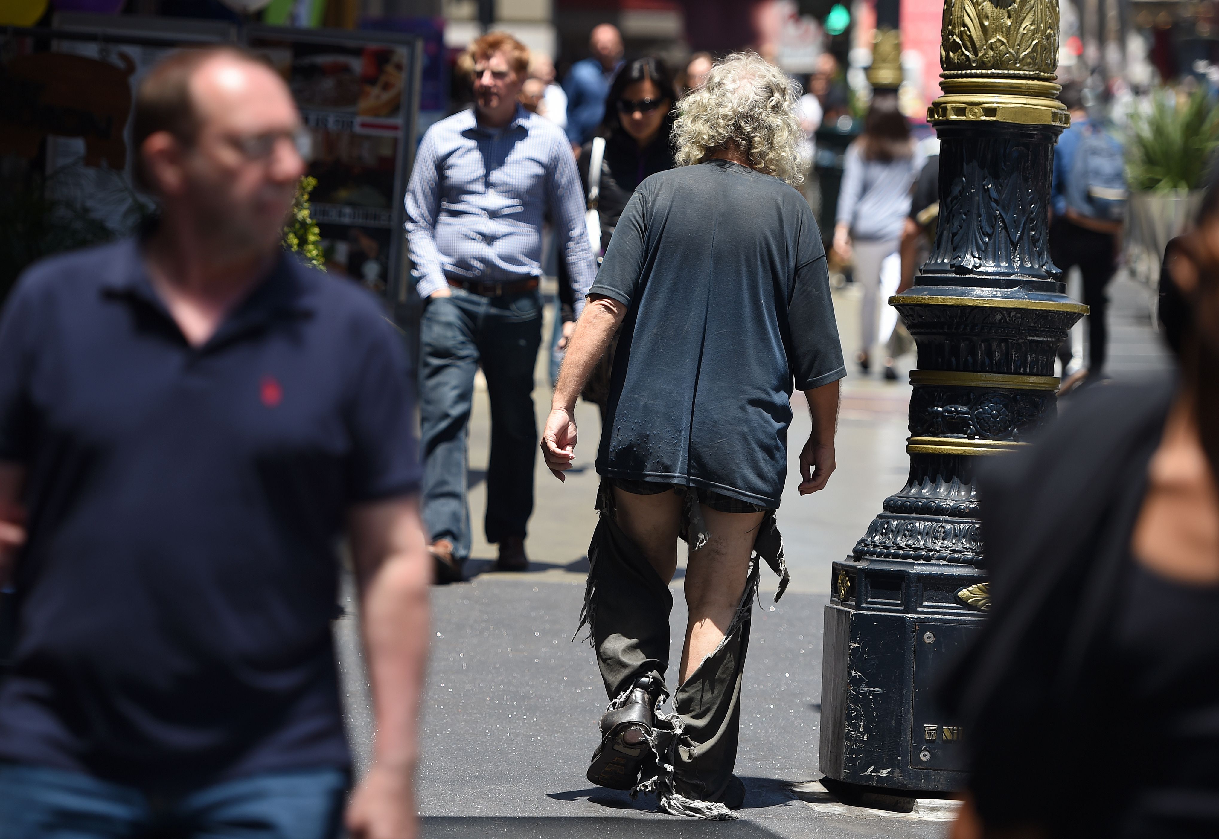 A homeless man walks in tattered clothing along a sidewalk in downtown San Francisco on June, 28, 2016. (Credit: Josh Edelson / AFP / Getty Images)