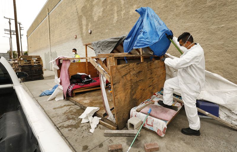 Two of those assisting cleanups at L.A. homeless encampments, Jesus Sanchez, left, and Javier Villarreal, make their way through one effort. (Credit: Al Seib / Los Angeles Times)