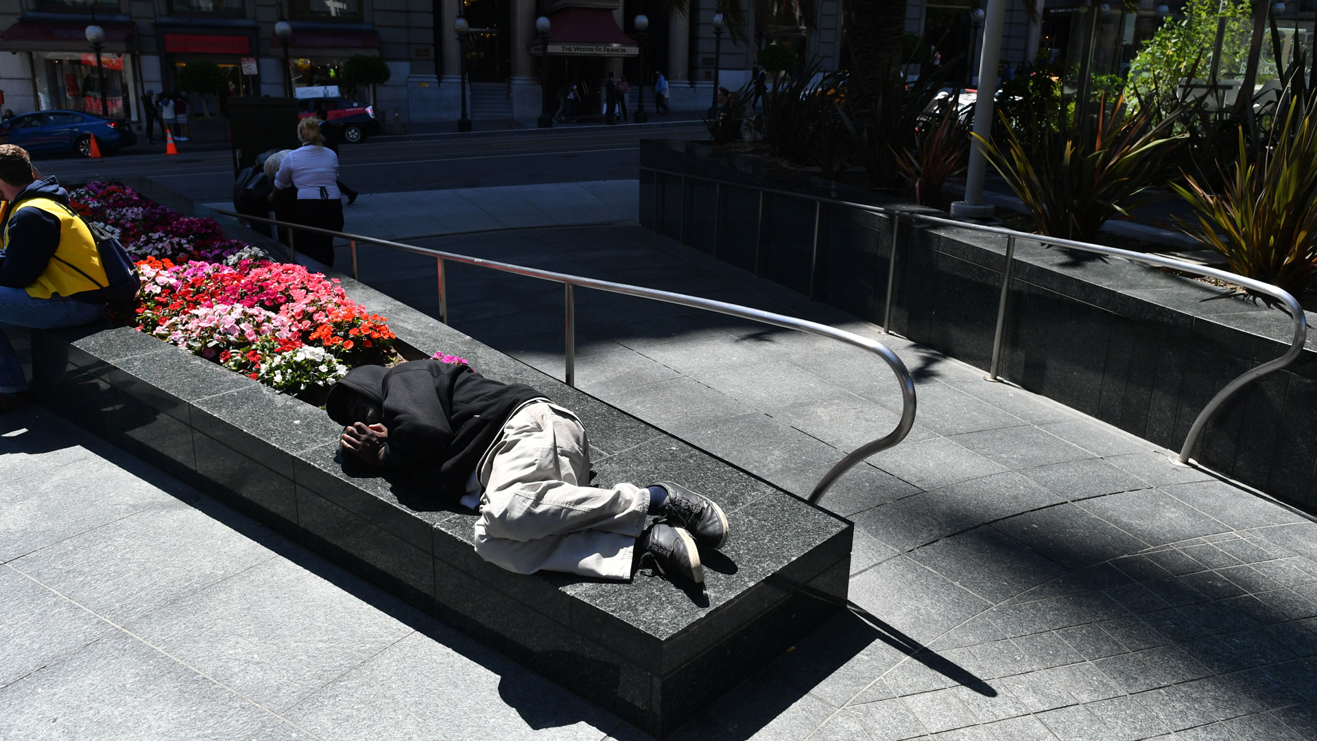 A homeless man sleeps on a planter in San Francisco, California on Tuesday, June, 28, 2016. (Credit: ;JOSH EDELSON/AFP/Getty Images)