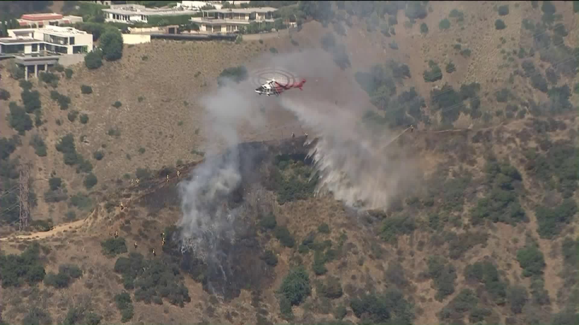 A helicopter drops water on a brush fire in Hollywood Hills West on Aug. 14, 2019. (Credit: KTLA)