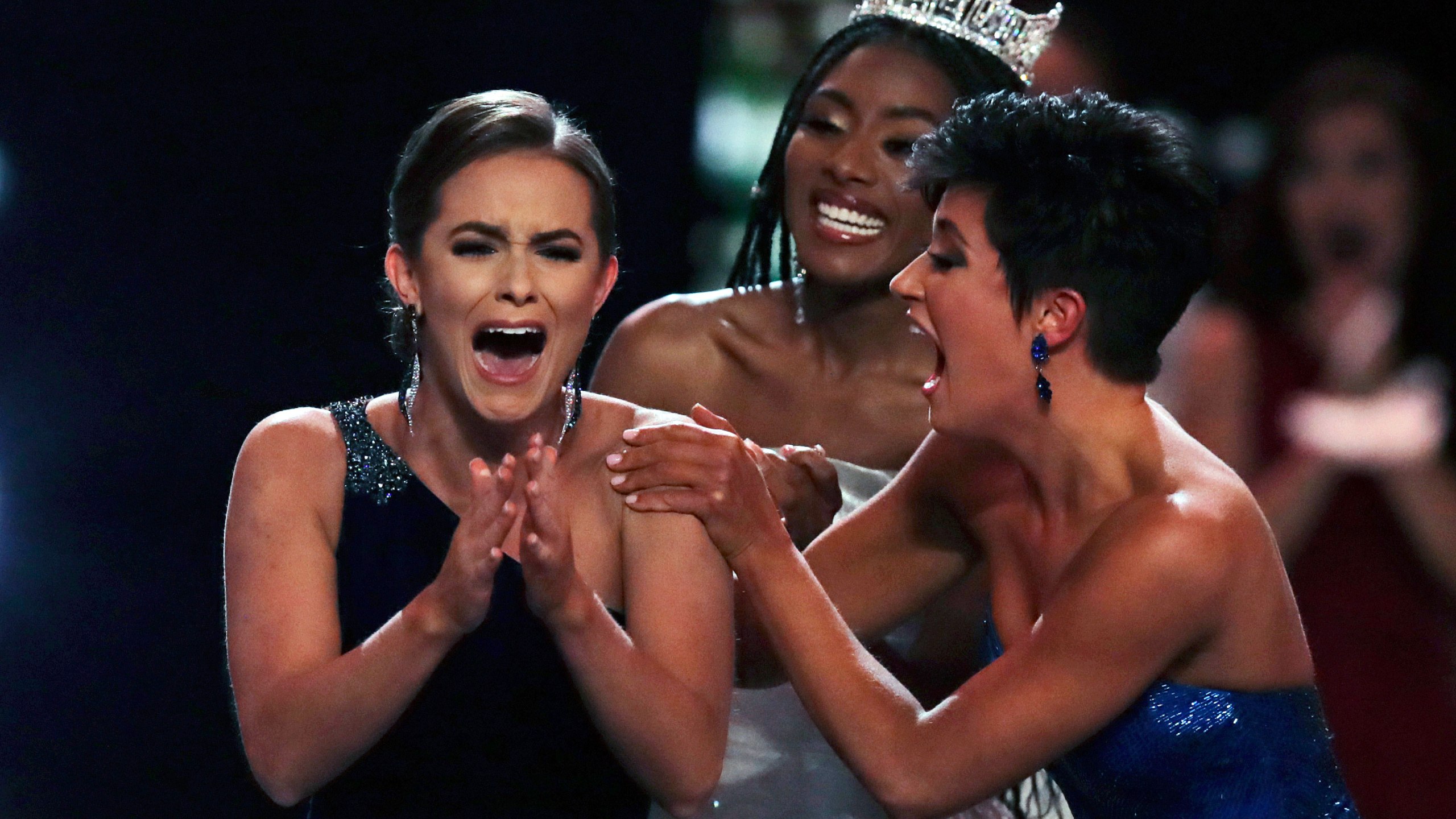 Camille Schrier, of Virginia, left, reacts after winning the Miss America competition at the Mohegan Sun casino in Uncasville, Conn., Thursday, Dec. 19, 2019. At right is runner-up Miss. Georgia Victoria Hill and and at rear is 2019 Miss. America Nia Franklin. (AP Photo/Charles Krupa, via CNN)