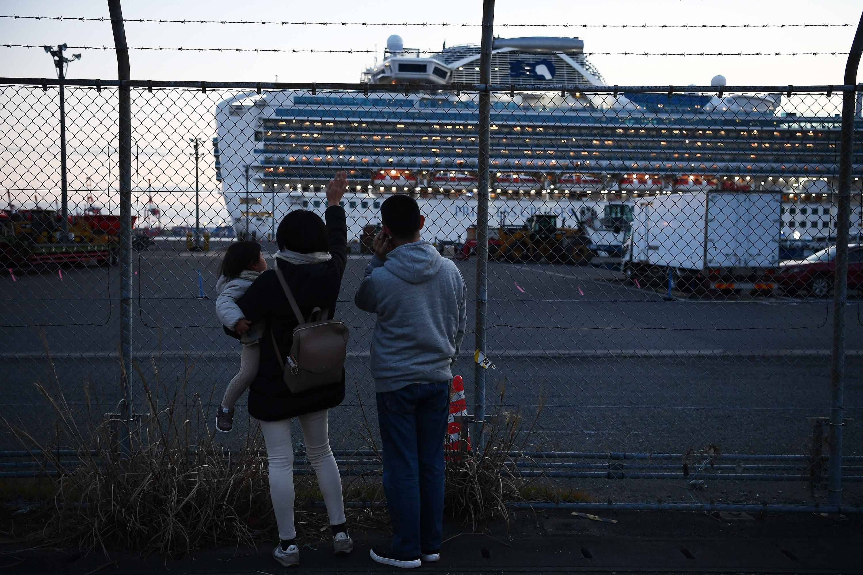 Relatives of passengers wave at the Diamond Princess cruise ship, with around 3,600 people quarantined onboard due to fears of coronavirus, as the ship departs from Daikoku Pier Cruise Terminal in Yokohama on Feb. 11, 2020. (Credit: Charly Triballeau/AFP via Getty Images)
