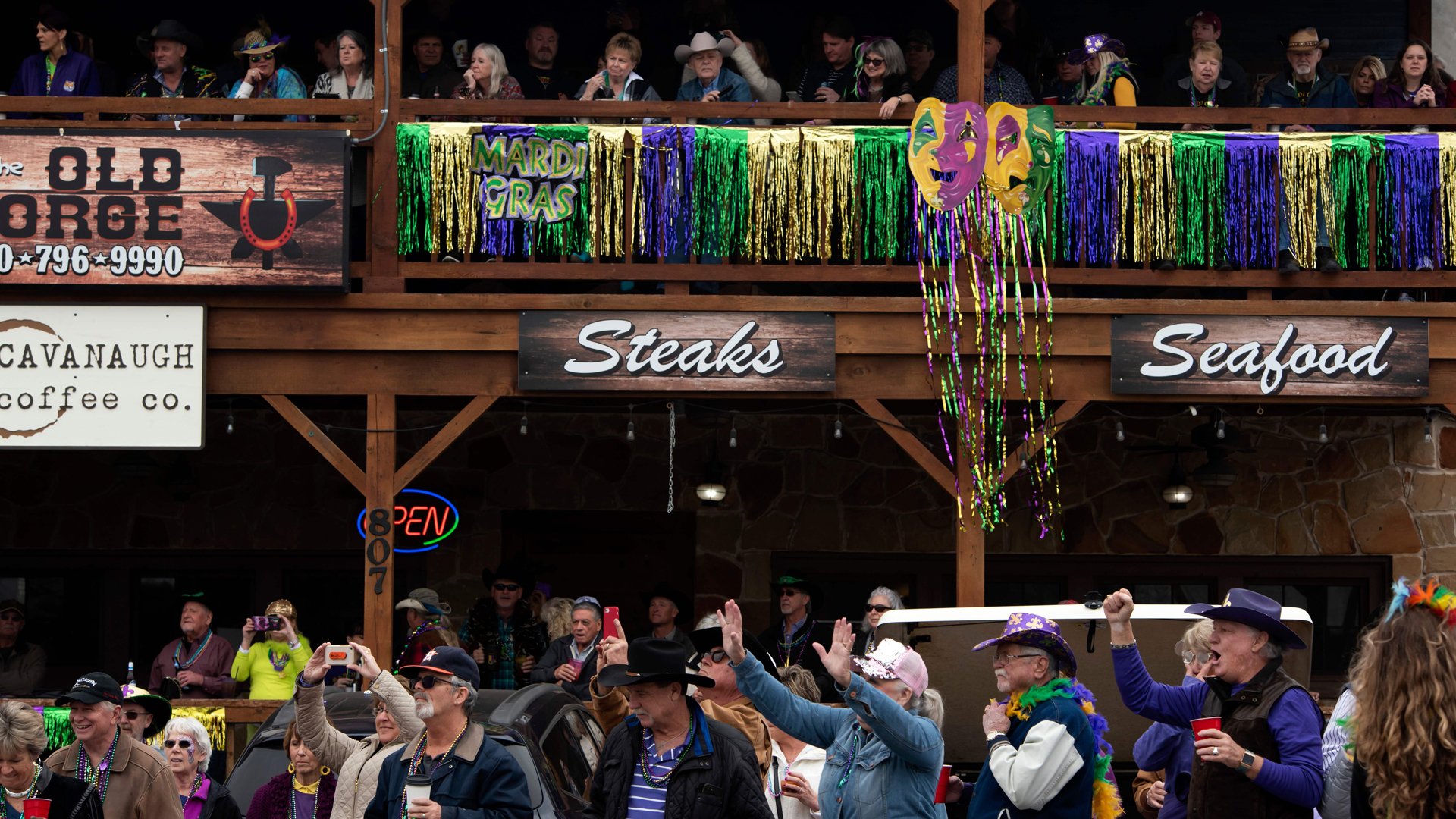 Revelers cheer as parade floats pass during the Cowboy Mardi Gras celebration in Bandera, Texas on February 15, 2020. (Credit: Mark Felix/AFP/Getty Images)
