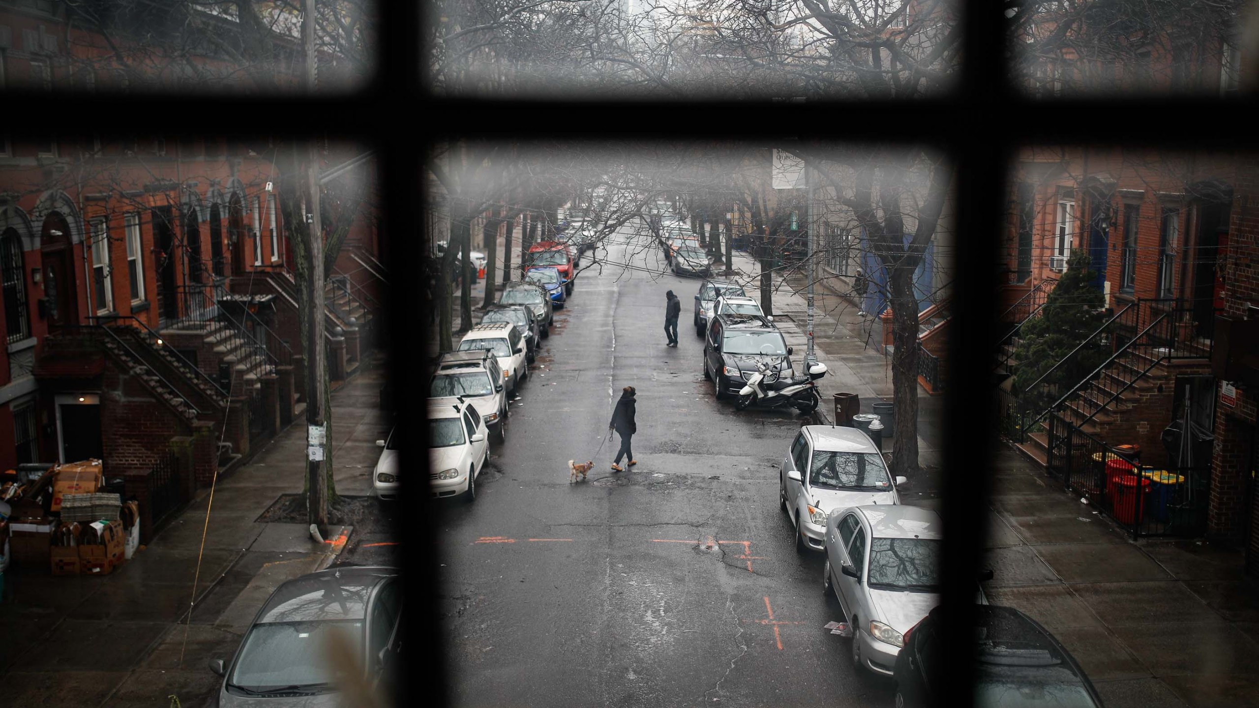 A pedestrian walks their dog through a quiet street, Tuesday, March 17, 2020, in the Brooklyn borough of New York. (AP Photo/John Minchillo)