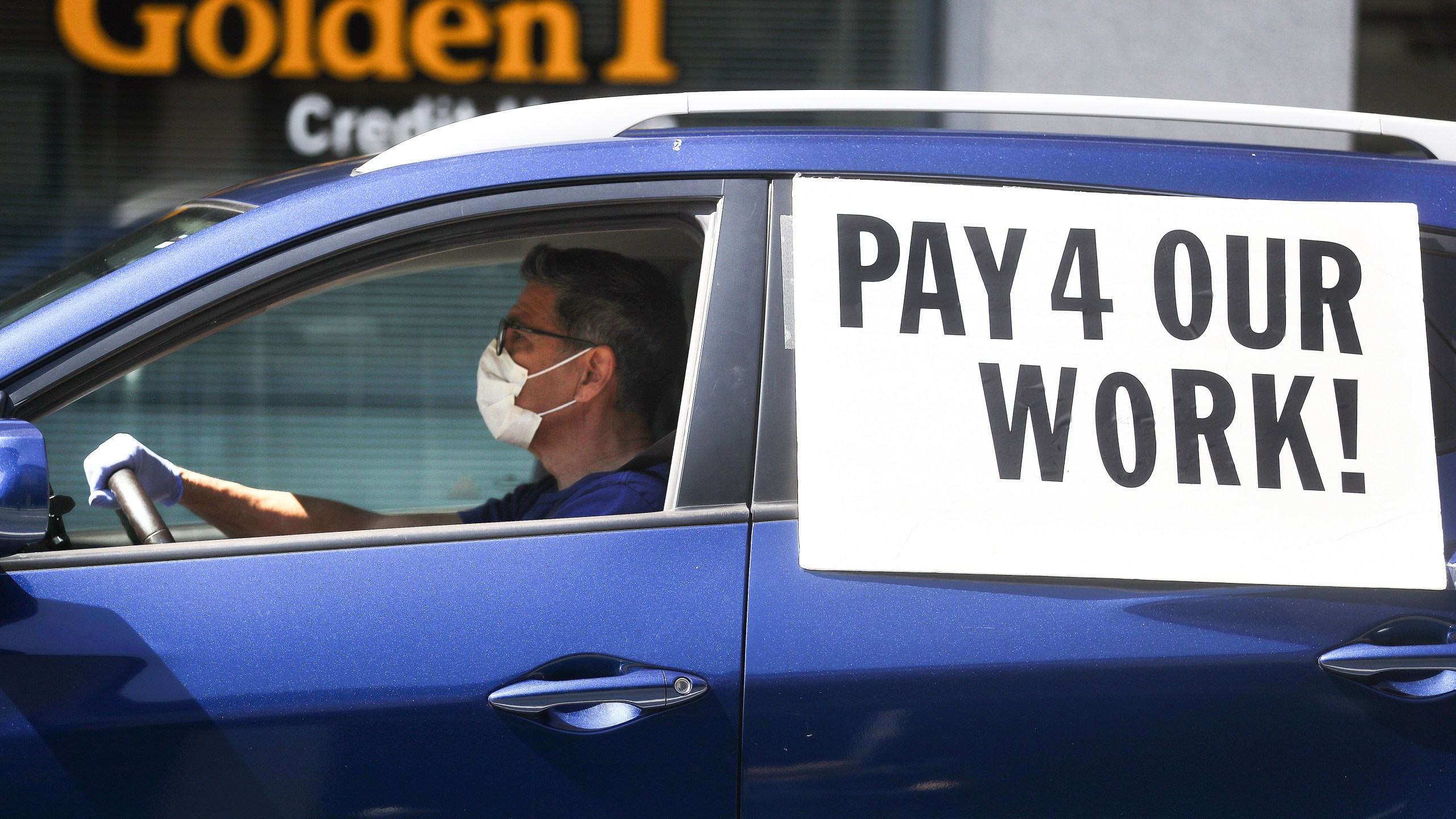 A driver wears a face mask and gloves as Uber and Lyft drivers with Rideshare Drivers United and the
 Transport Workers Union of America conduct a" "caravan protest" outside the California Labor Commissioner’s office amidst the coronavirus pandemic on April 16, 2020 in Los Angeles. (Mario Tama/Getty Images)