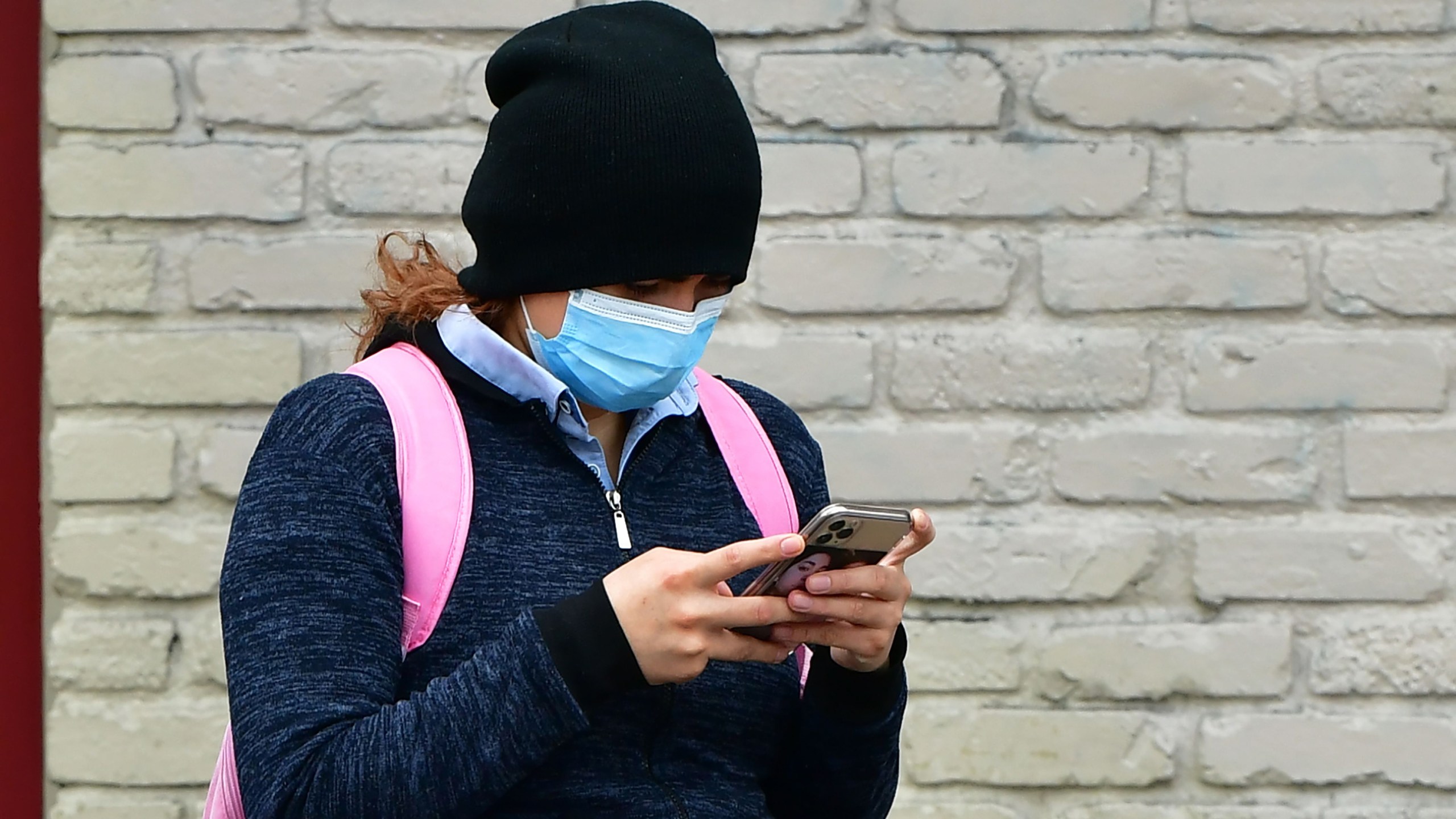 A woman wears a face mask while checking her cellphone in Los Angeles, on April 6, 2020. (FREDERIC J. BROWN/AFP via Getty Images)