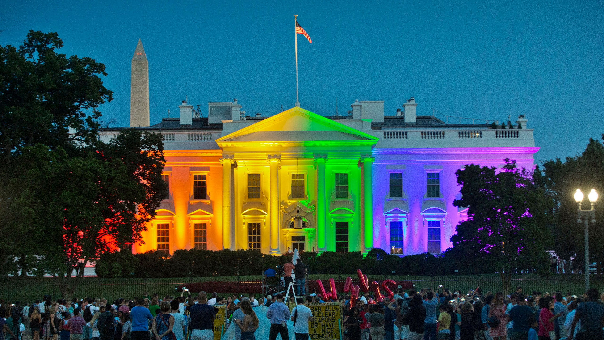 In this Friday, June 26, 2015 file photo, people gather in Lafayette Park to see the White House illuminated with rainbow colors in commemoration of the Supreme Court's ruling to legalize same-sex marriage in Washington. The Trump administration Friday, June 12, 2020, finalized a regulation that overturns Obama-era protections for transgender people against sex discrimination in health care. (AP Photo/Pablo Martinez Monsivais, File)