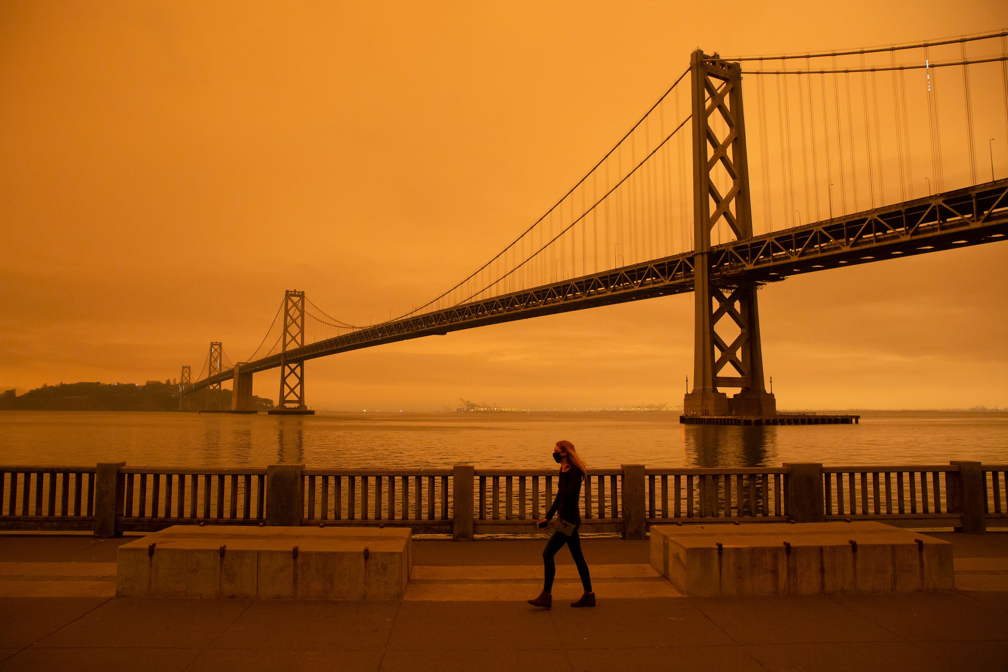 A woman walks along The Embarcadero under an orange smoke-filled sky in San Francisco on Sept. 9, 2020. (Brittany Hosea-Small / AFP / Getty Images)