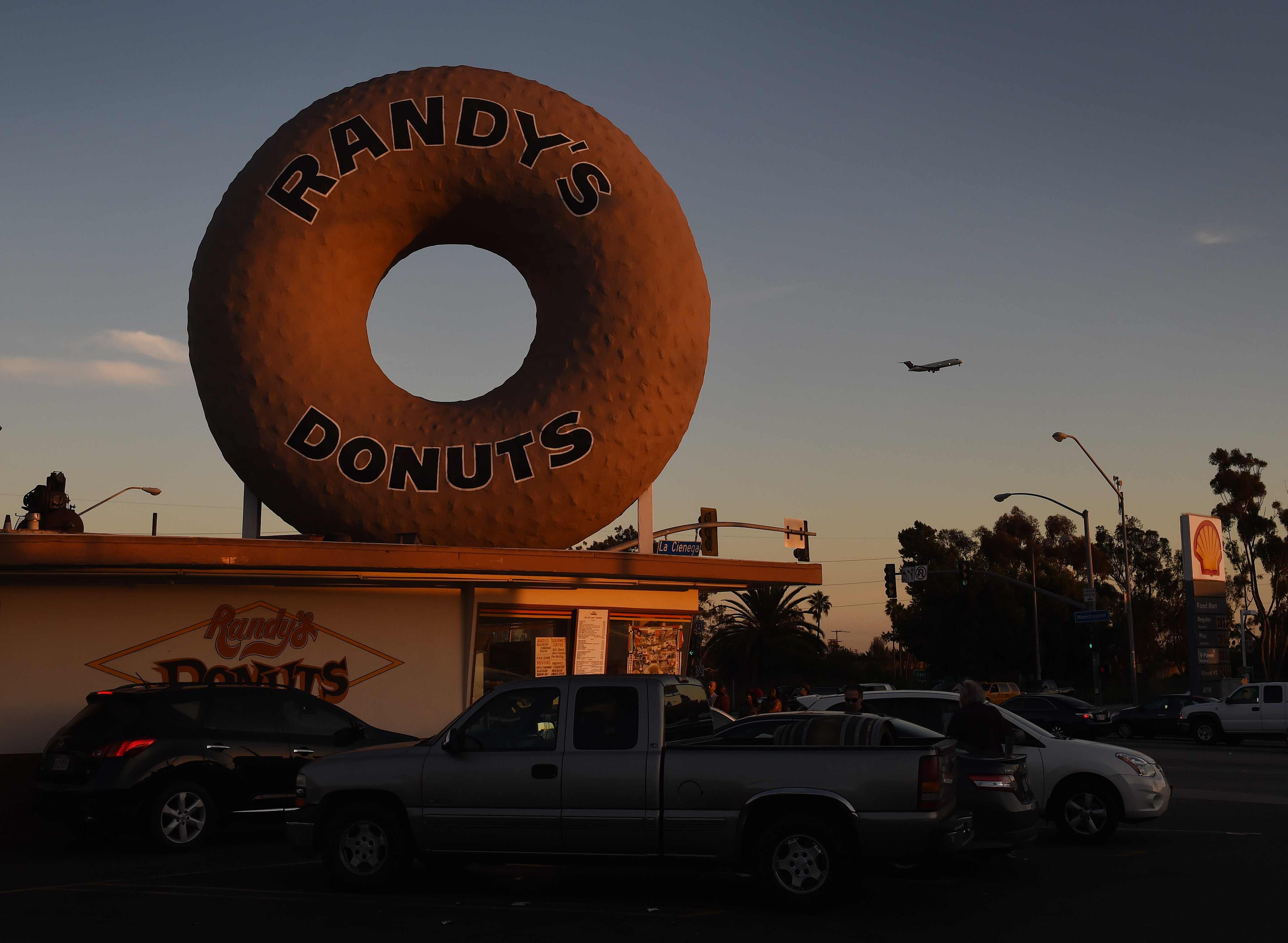 A Swissair plane flies past Randy's Donuts which is an iconic landmark in the city of Inglewood, as it makes its descent into Los Angeles International Airport, California on January 24, 2016. The recent announcement that the St. Louis Rams football team will relocate to a new stadium in Inglewood has started a property boom in the surrounding area. AFP PHOTO / MARK RALSTON / AFP / MARK RALSTON (Photo credit should read MARK RALSTON/AFP via Getty Images)