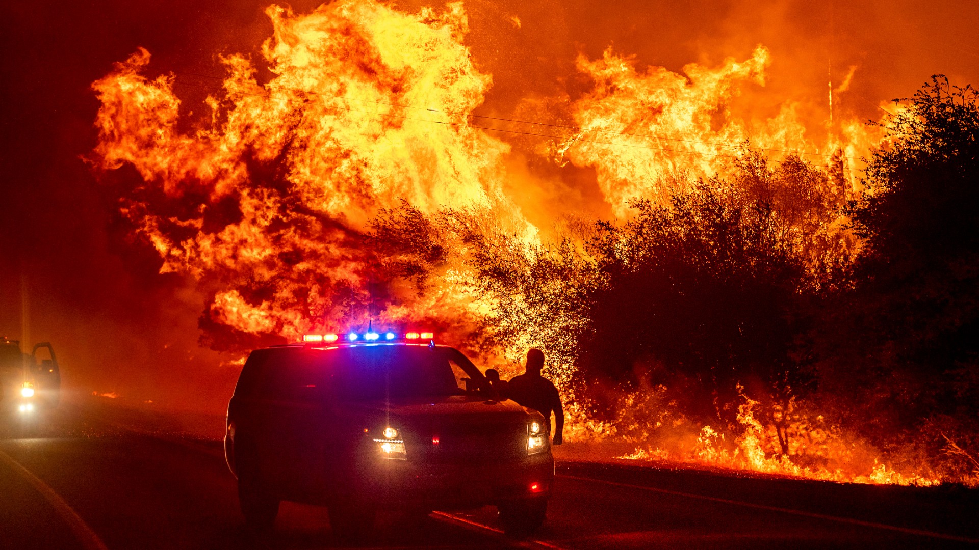 Flames lick above vehicles on Highway 162 as the Bear Fire burns in Oroville, California, on Sept. 9, 2020. (Noah Berger / Associated Press)