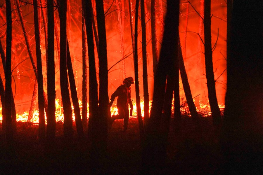 In this Monday, Sept. 14, 2020 file photo, a firefighter is silhouetted against a fire burning outside the village of Roqueiro, near Oleiros, Portugal. (AP Photo/Sergio Azenha, File)