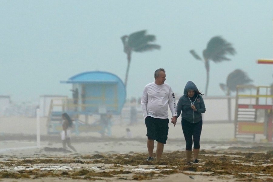 A couple walks along the beach during a downpour, Sunday, Nov. 8, 2020, on Miami Beach, Florida's famed South Beach. (AP Photo/Wilfredo Lee)