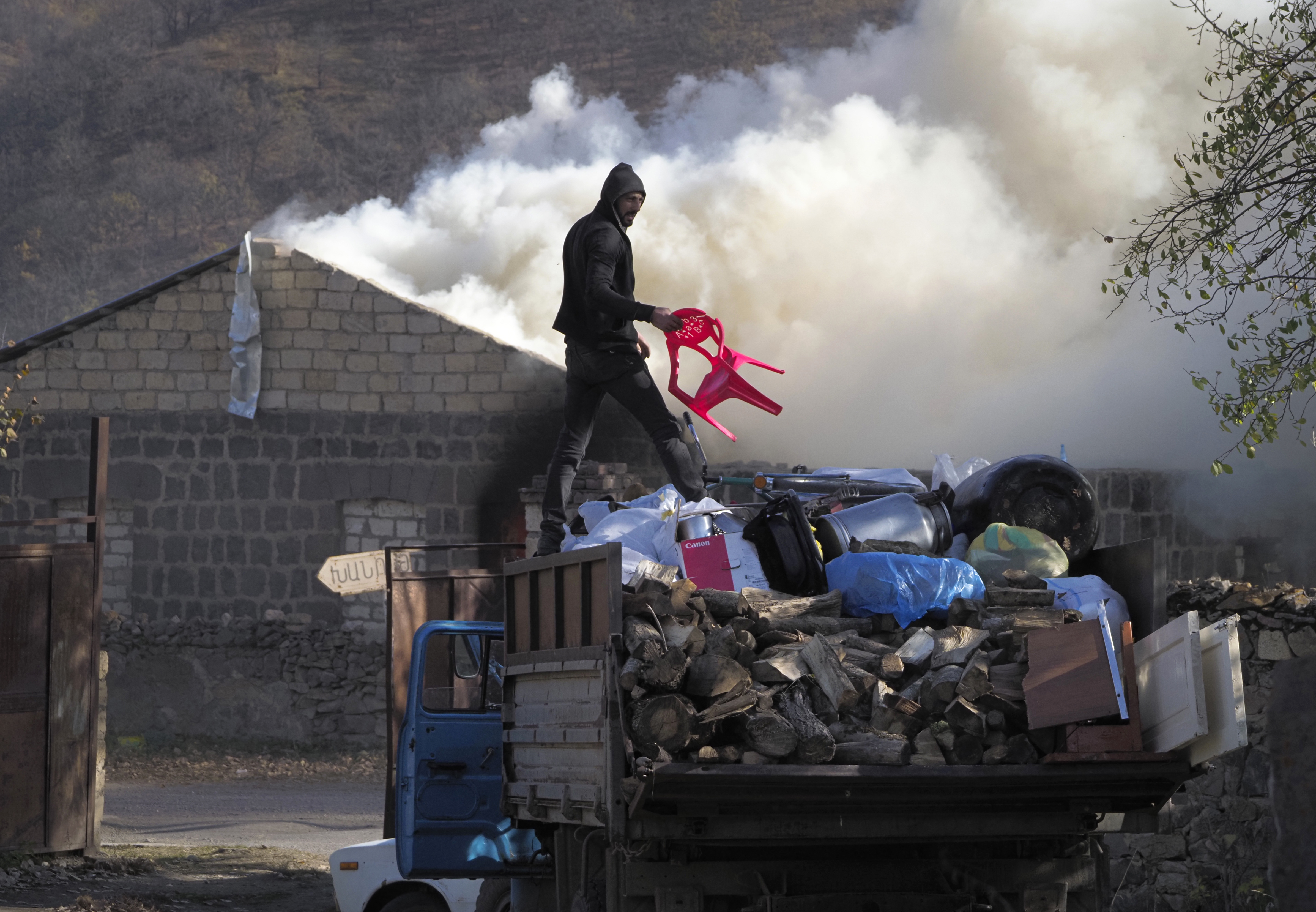 A man loads possessions on his truck after setting his home on fire, in an area once occupied by Armenian forces but is soon to be turned over to Azerbaijan, in Karvachar, the separatist region of Nagorno-Karabakh, on Friday, Nov. 13, 2020. (Dmitry Lovetsky/AP Photo)