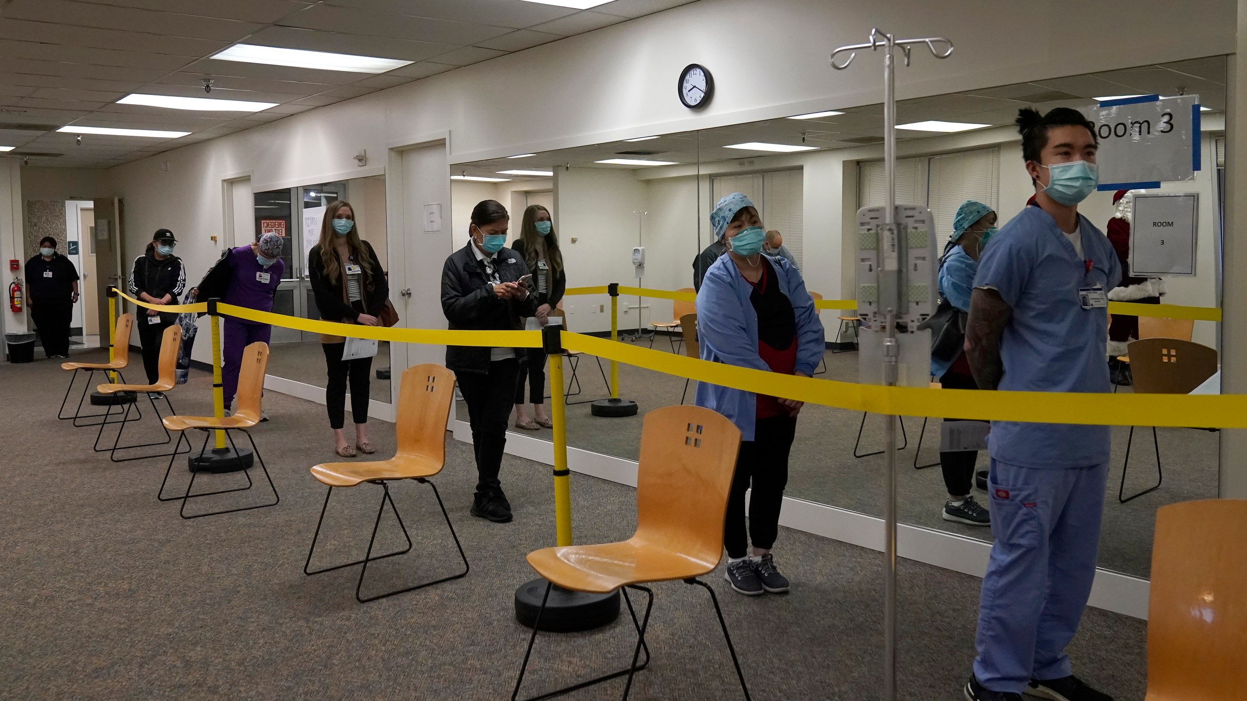 Health care workers wait in line to receive the Pfizer-BioNTech COVID-19 vaccine at Seton Medical Center in Daly City, Calif., Thursday, Dec. 24, 2020. (AP Photo/Jeff Chiu)