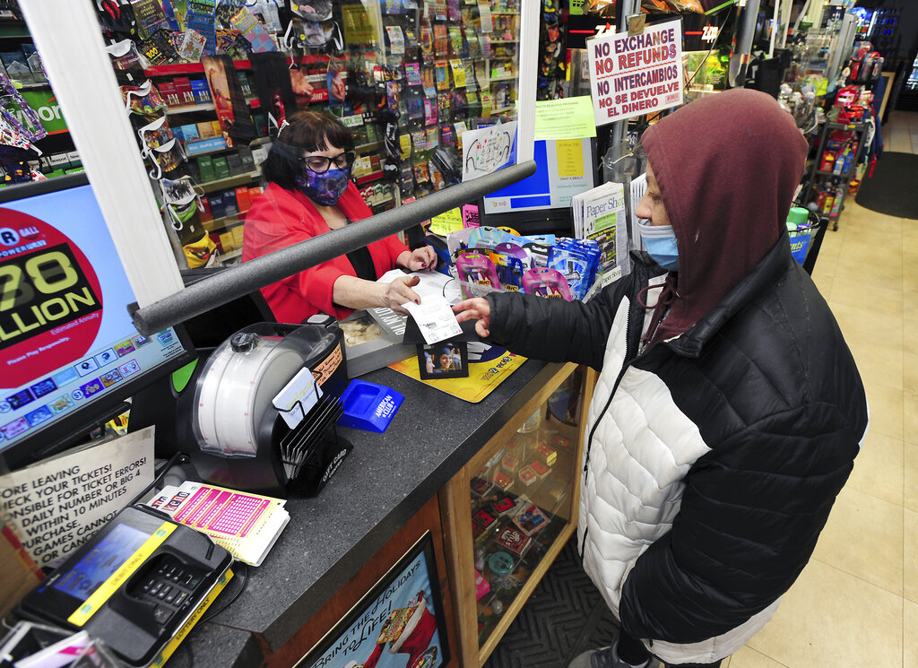 Jacqueline Donahue of Hazleton, right, buys la Mega Millions lottery ticket at the Anthracite Newsstand on Public Square, Monday, Jan. 18, 2021, in Wilkes-Barre, Pa. (Mark Moran/The Citizens' Voice via AP)