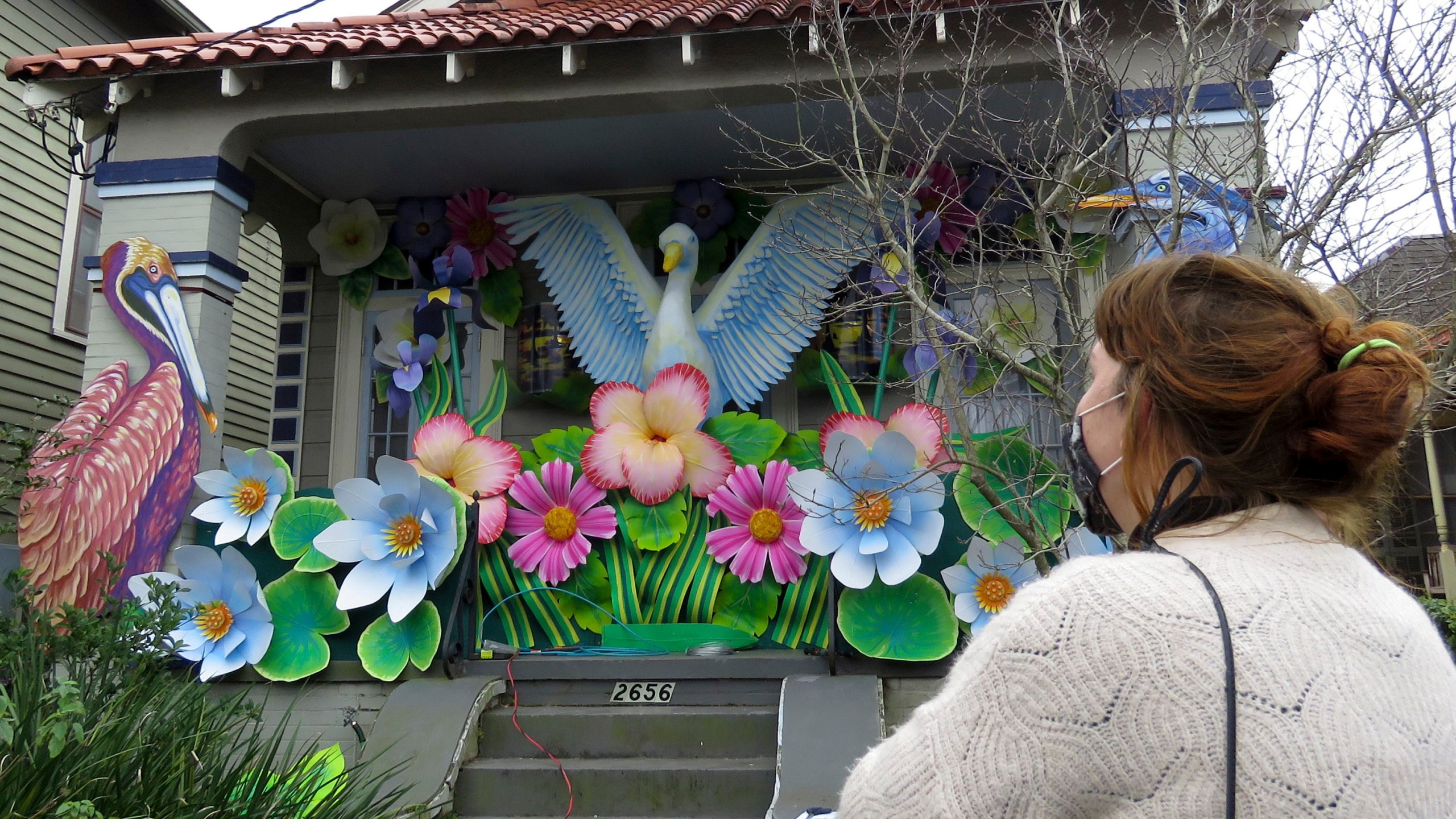 Designer Caroline Thomas looks at a house decorated like a parade float in New Orleans on Friday, Jan. 8, 2021. All around the city, thousands of houses are being decorated as floats because the coronavirus pandemic has canceled parades that usually take place on Mardi Gras. (AP Photo/Janet McConnaughey)