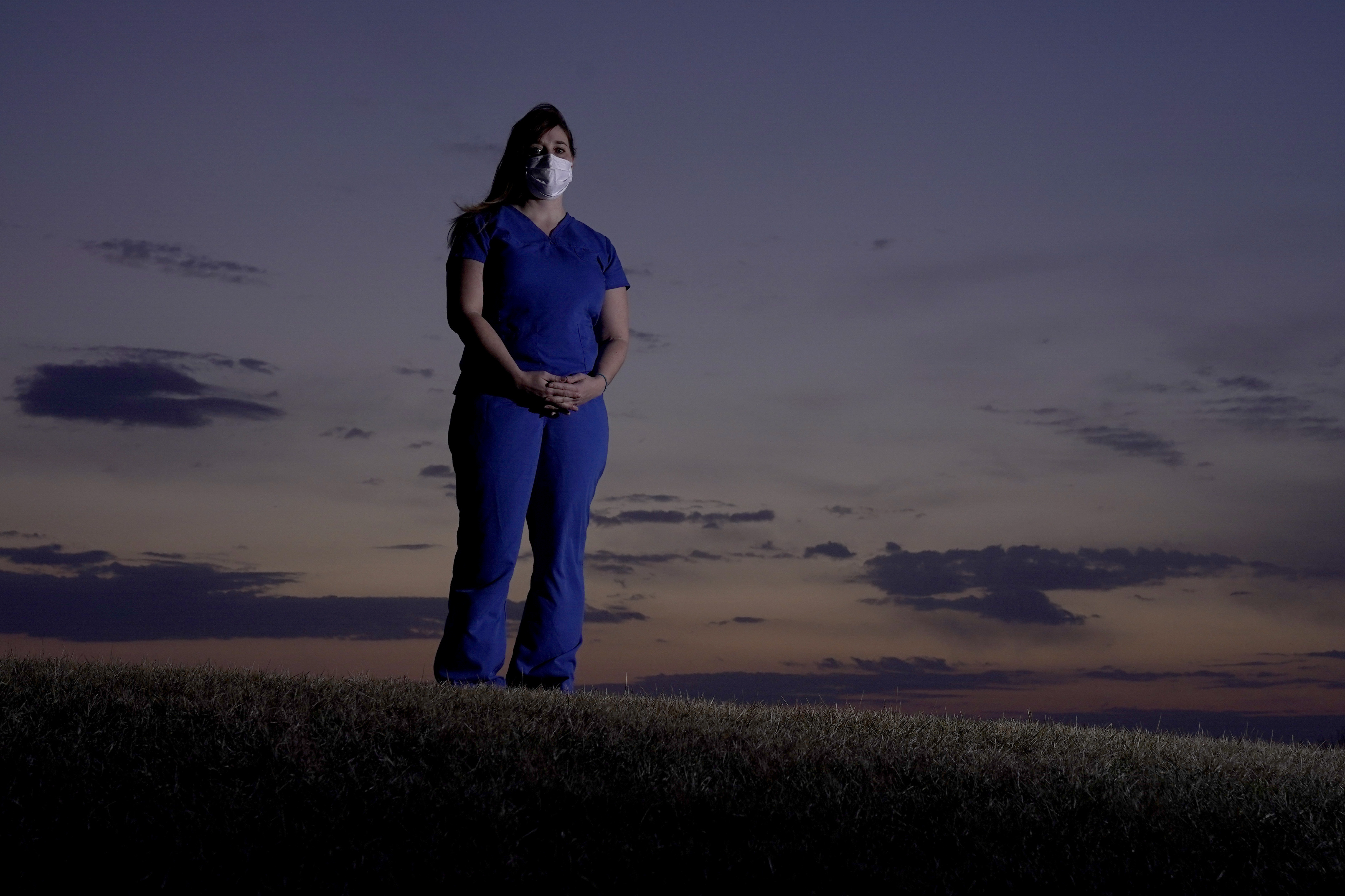Emergency room nurse L'Erin Ogle stands at dawn before starting her 12-hour shift at a nearby hospital Tuesday, March 9, 2021, in Overland Park, Kan. (AP Photo/Charlie Riedel)