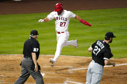 Los Angeles Angels' Mike Trout, center, scores on a single by Justin Upton as Chicago White Sox starting pitcher Lucas Giolito, right, covers the plate and home plate umpire Larry Vanover watches during the fourth inning of an Opening Day baseball game Thursday, April 1, 2021, in Anaheim, Calif. (AP Photo/Mark J. Terrill)