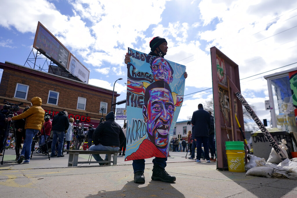 In this Wednesday, April 21, 2021, file photo, a man holds a sign at George Floyd Square, in Minneapolis, a day after former Minneapolis police Officer Derek Chauvin was convicted on all counts for the 2020 death of Floyd. (AP Photo/Julio Cortez, File)