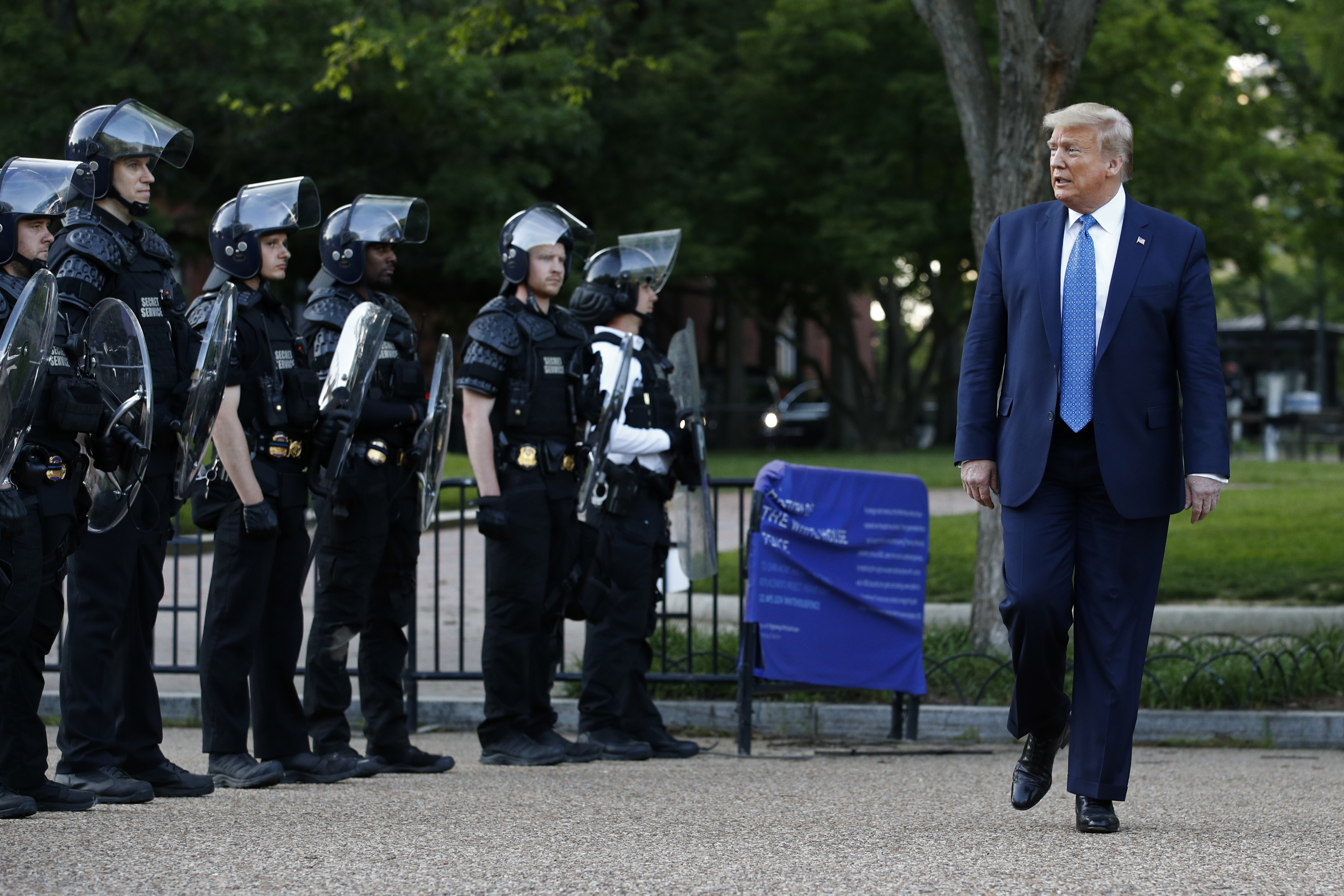 In this June 1, 2020 file photo, President Donald Trump walks past police in Lafayette Park after visiting outside St. John's Church across from the White House in Washington. (AP Photo/Patrick Semansky)