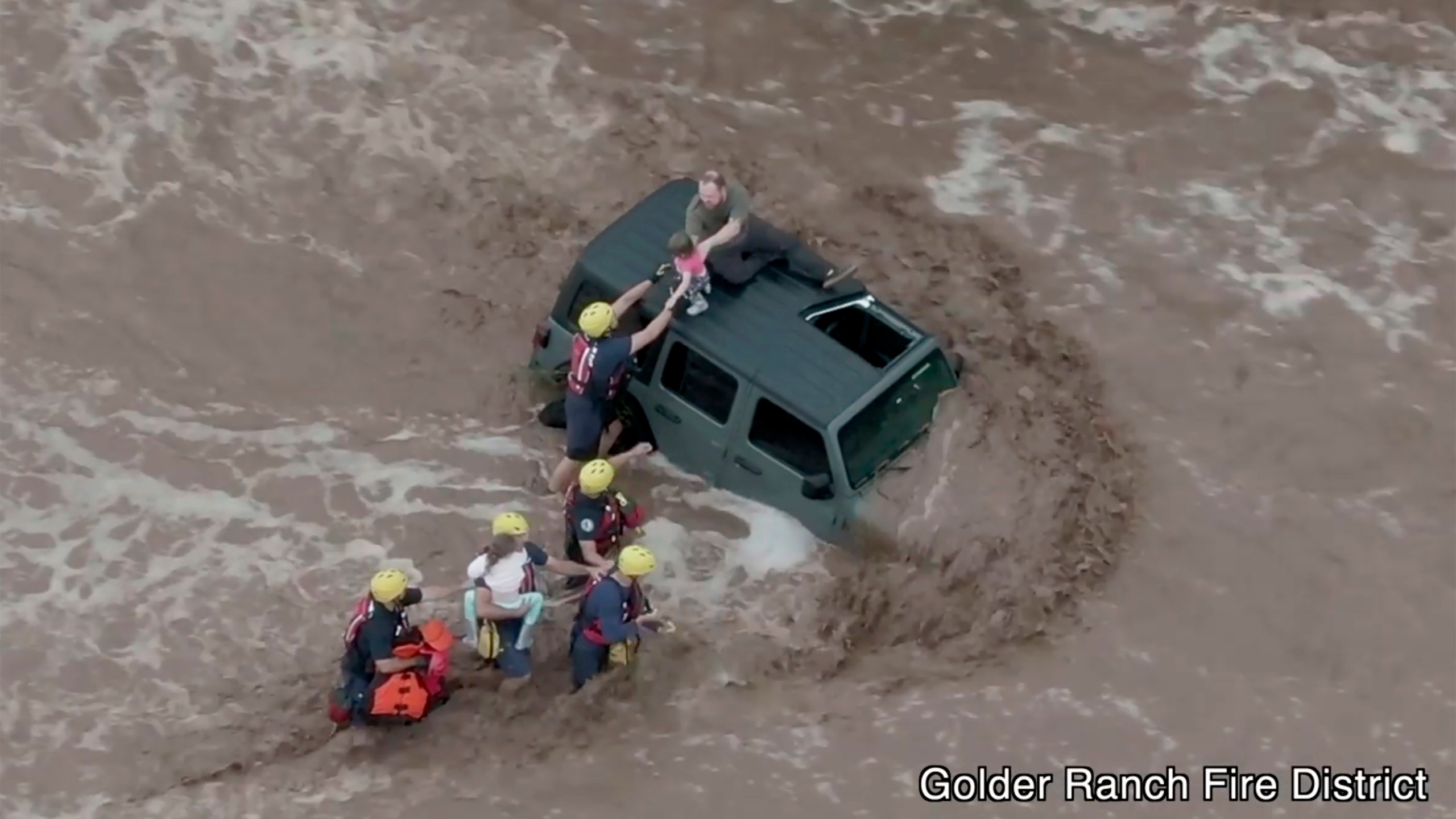 This drone image provided by the Golder Ranch Fire District shows firefighters safely rescue a man and his two daughters from the roof of their vehicle after it was swept away in fast moving water just north of Tucson, Ariz., on July 14, 2021. (Golder Ranch Fire District via Associated Press)