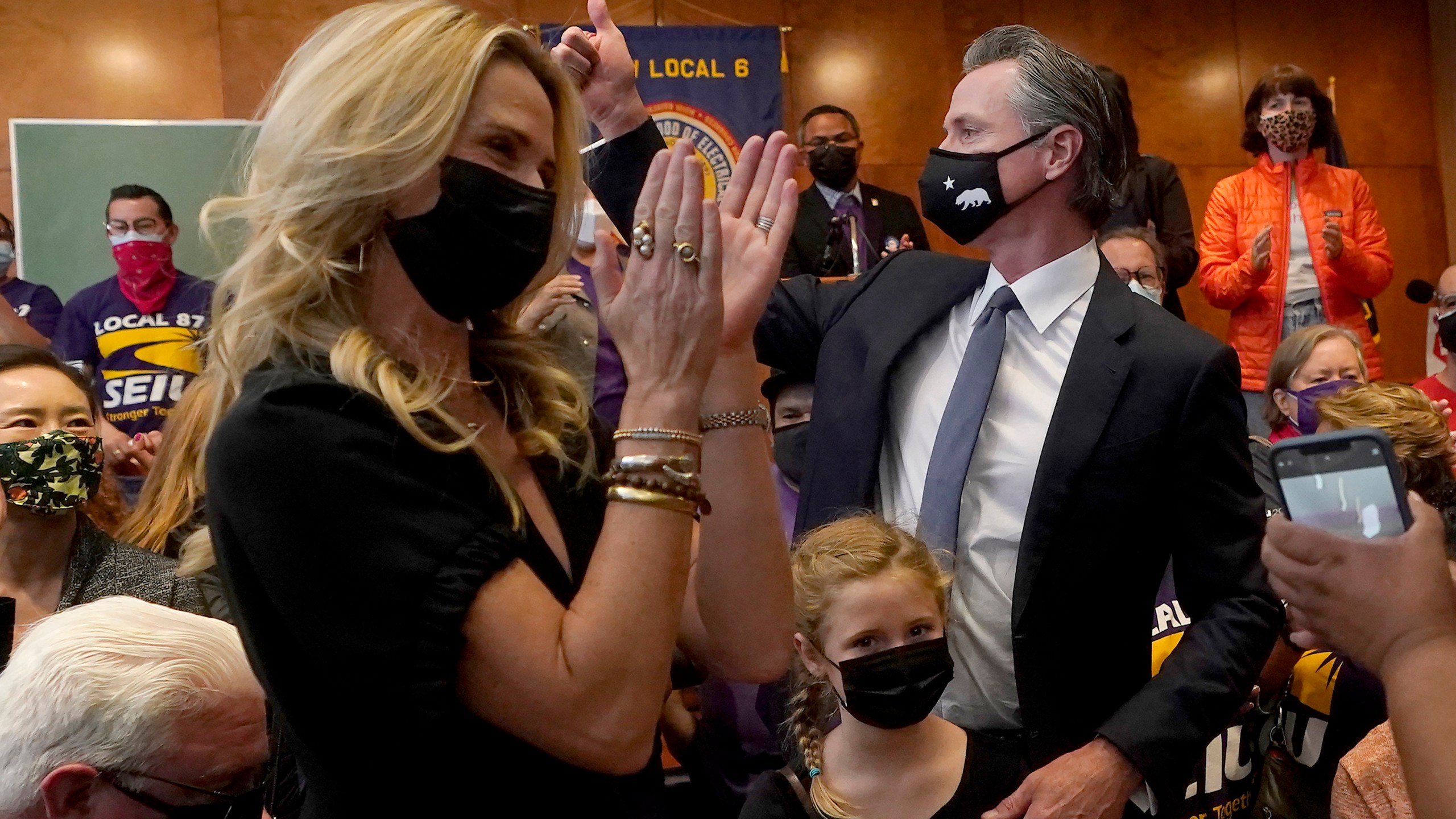 Gov. Gavin Newsom, middle right, gestures next to his wife, Jennifer Siebel Newsom, foreground, and their daughter, Brooklynn, bottom, after speaking to volunteers in San Francisco, Tuesday, Sept. 14, 2021. The recall election that could remove California Democratic Gov. Newsom is coming to an end. Voting concludes Tuesday in the rare, late-summer election that has emerged as a national battlefront on issues from COVID-19 restrictions to climate change. (AP Photo/Jeff Chiu)