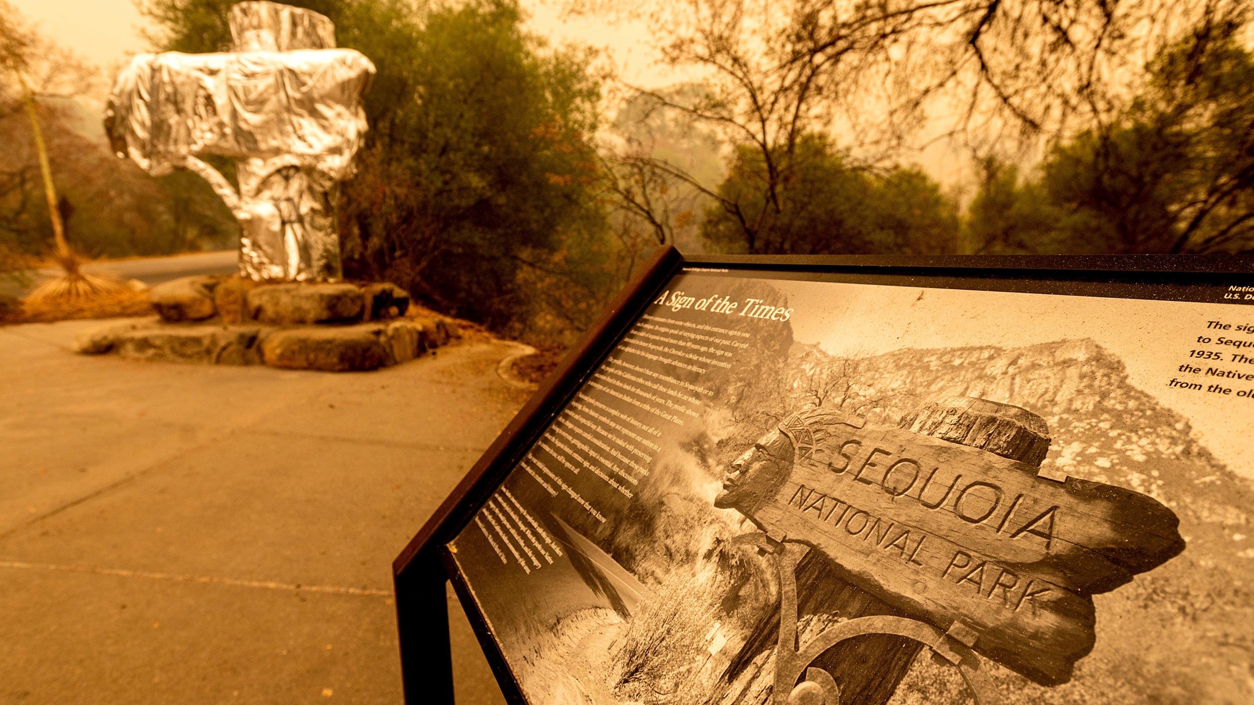 Fire-resistant wrap covers a historic welcome sign as the KNP Complex Fire burns in Sequoia National Park, Calif., on Wednesday, Sept. 15, 2021. The blaze is burning near the Giant Forest, home to more than 2,000 giant sequoias. (AP Photo/Noah Berger)