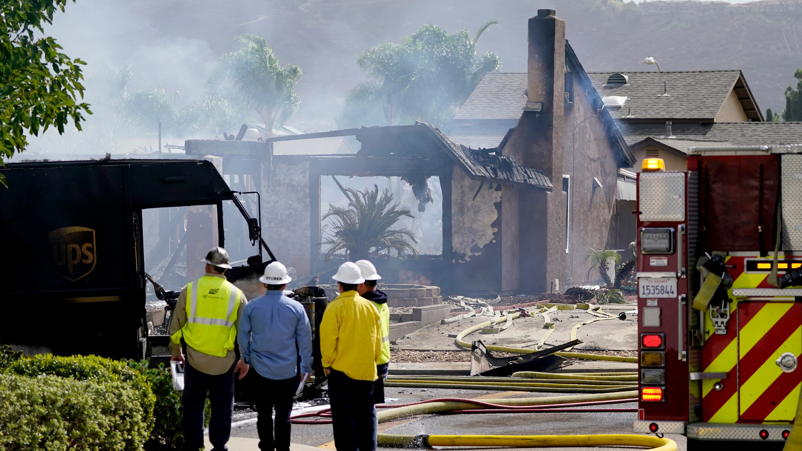 Fire and safety crews work the scene of a plane crash, Monday, Oct. 11, 2021, in Santee, Calif. At least two people were killed and two others were injured when the small plane crashed into a suburban Southern California neighborhood, setting two homes ablaze, authorities said. (AP Photo/Gregory Bull)