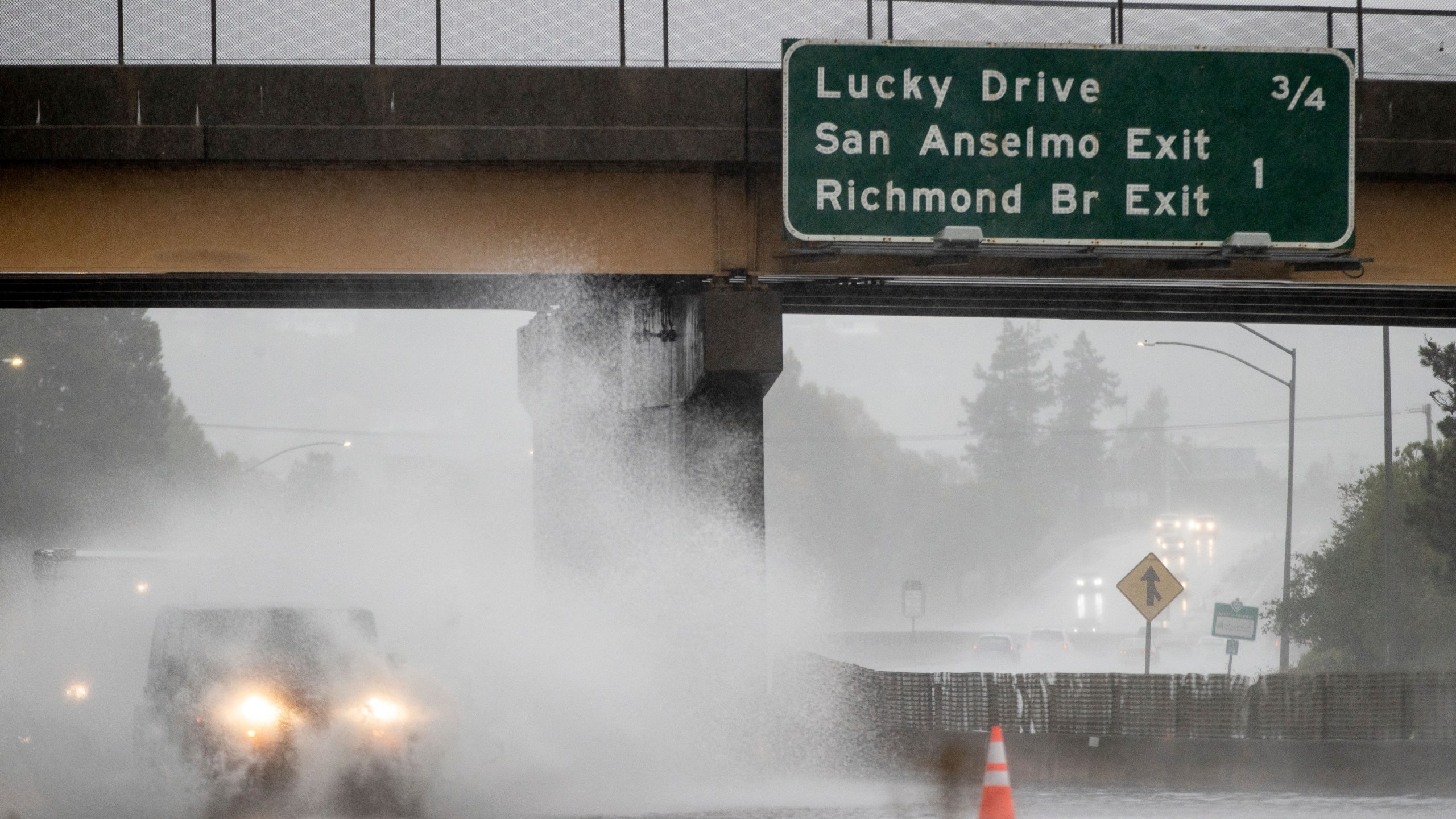 A car drives on Highway 101, which is partially flooded in Corte Madera, Calif., Sunday, Oct. 24, 2021. (AP Photo/Ethan Swope)