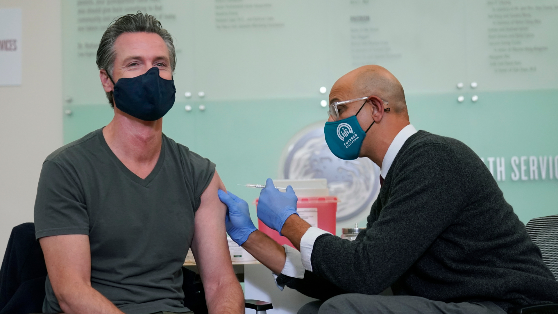 Gov. Gavin Newsom, left, receives a Moderna COVID-19 vaccine booster shot from California Health and Human Services Secretary Dr. Mark Ghaly at Asian Health Services in Oakland on Oct. 27, 2021. (AP Photo/Jeff Chiu)