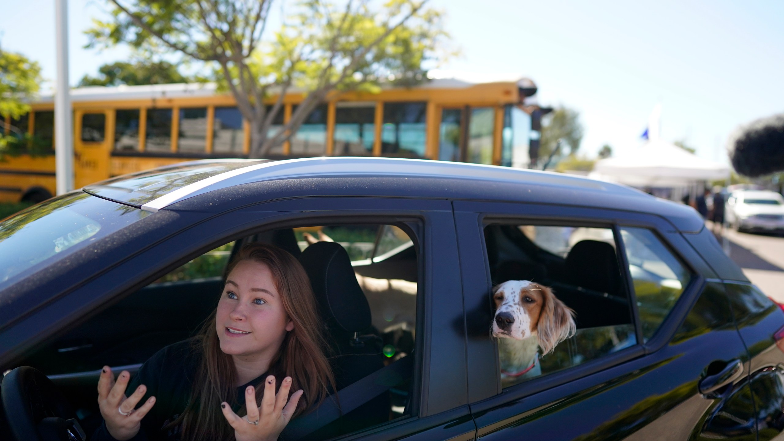 Brooklyn Pittman talks as she sits in her car with her dogs after receiving food from an Armed Services YMCA food distribution, Oct. 28, 2021, in San Diego. (AP Photo/Gregory Bull)