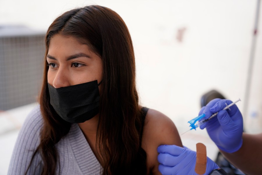 A young woman from Tijuana, Mexico, receives a vaccination shot against the coronavirus outside of the Mexican Consulate building on Nov. 18, 2021, in San Diego. Scores of Mexican adolescents were bused to California to get vaccinated against the coronavirus as efforts get underway across Mexico to get shots in the arms of teens. (AP Photo/Gregory Bull)