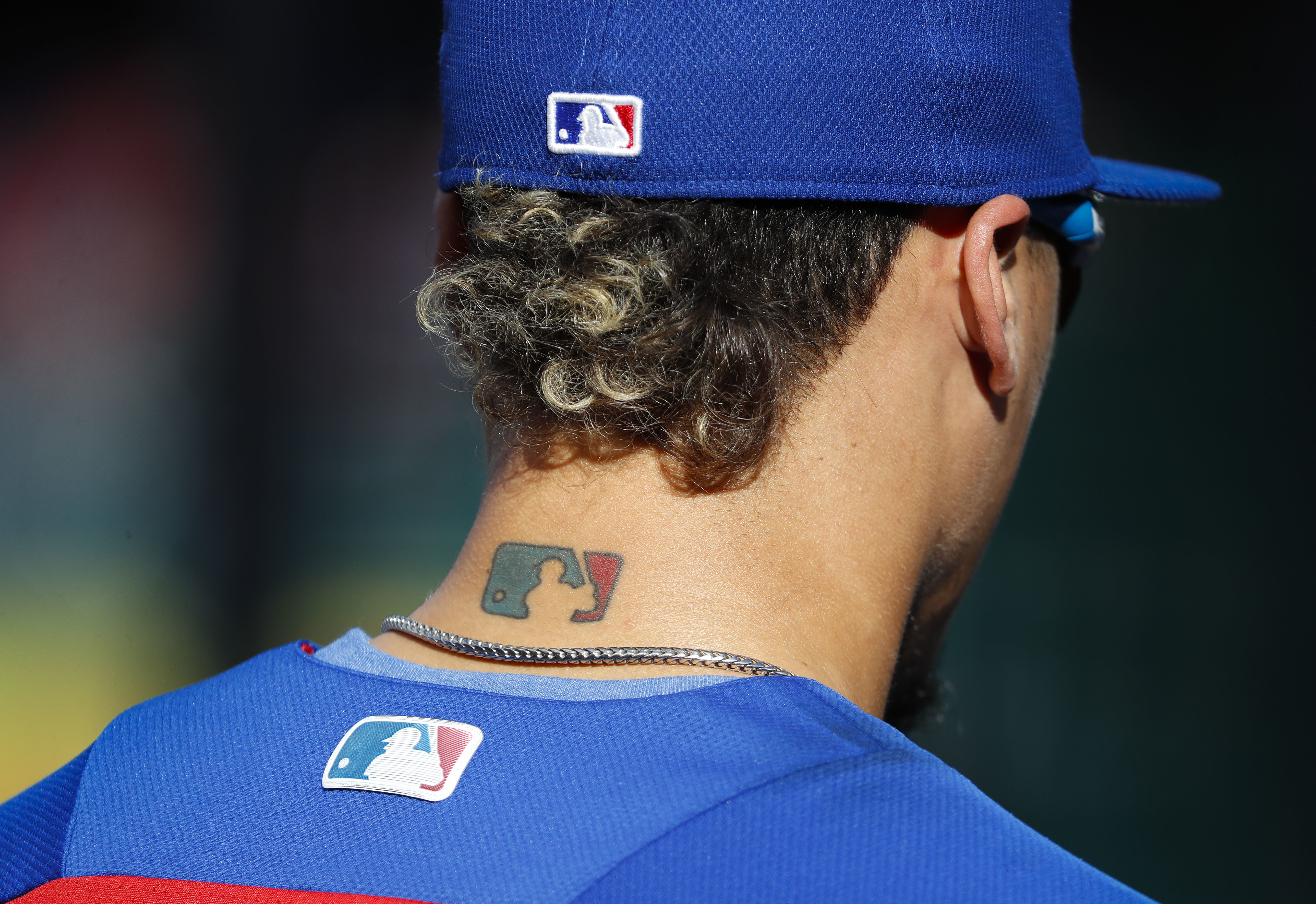 Then-Chicago Cubs' Javier Baez sports an MLB logo tattoo and logos on his hat and jersey as he waits to take batting practice before Game 2 of baseball's National League Division Series against the Washington Nationals at Nationals Park, Saturday, Oct. 7, 2017, in Washington. The clock ticked down toward the expiration of Major League Baseball’s collective bargaining agreement at 11:59 p.m. EST Wednesday night, Dec. 1, 2021, and what was likely to be a management lockout ending the sport’s labor peace at over 26 1/2 years. (AP Photo/Pablo Martinez Monsivais, File)