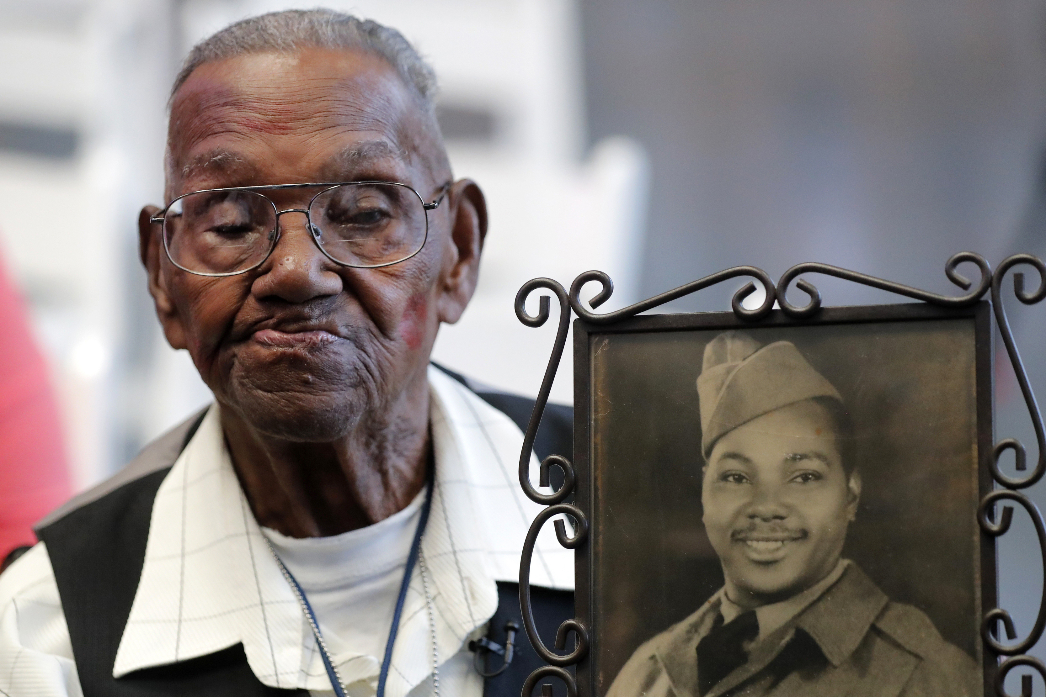 World War II veteran Lawrence Brooks holds a photo of him taken in 1943, as he celebrates his 110th birthday at the National World War II Museum in New Orleans, on Sept. 12, 2019. Brooks, the oldest World War II veteran in the U.S. — and believed to be the oldest man in the country — died on Wednesday, Jan. 5, ,2022 at the age of 112. (AP Photo/Gerald Herbert, File)
