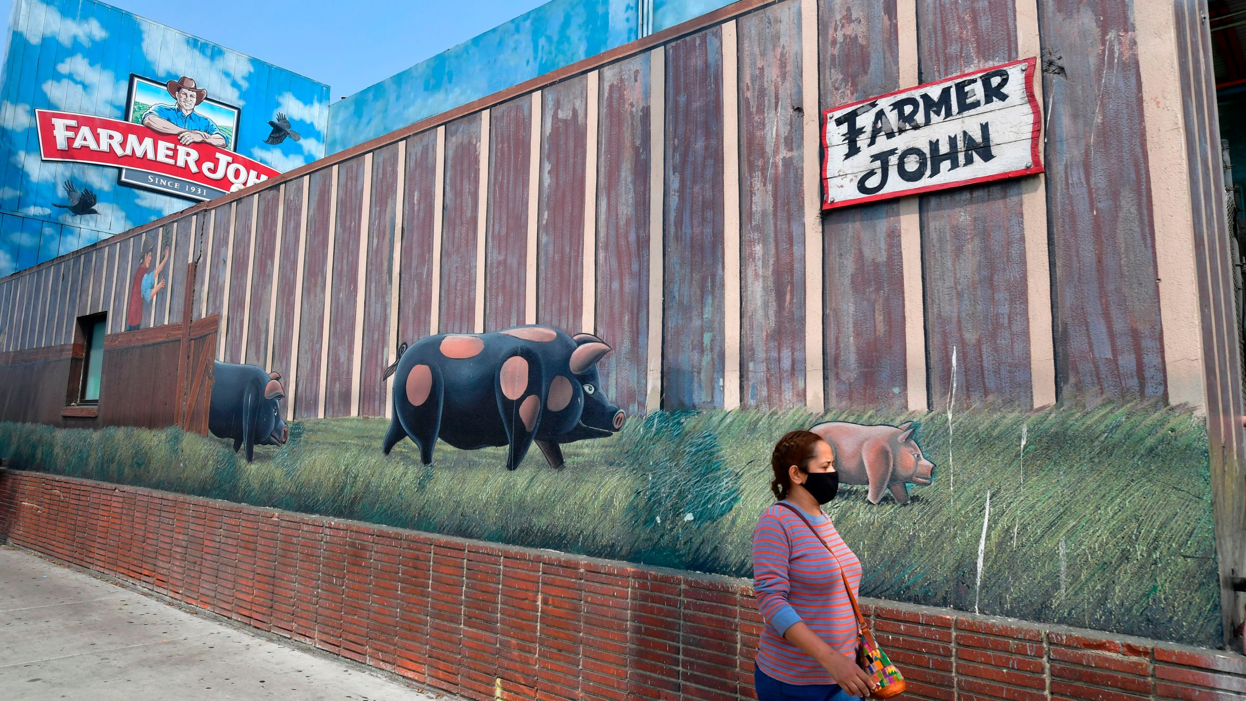 A woman wears a facemask while walking past the Farmer John Slaughterhouse/Packing plant in Vernon on Sept. 14, 2020. (FREDERIC J. BROWN/AFP via Getty Images)