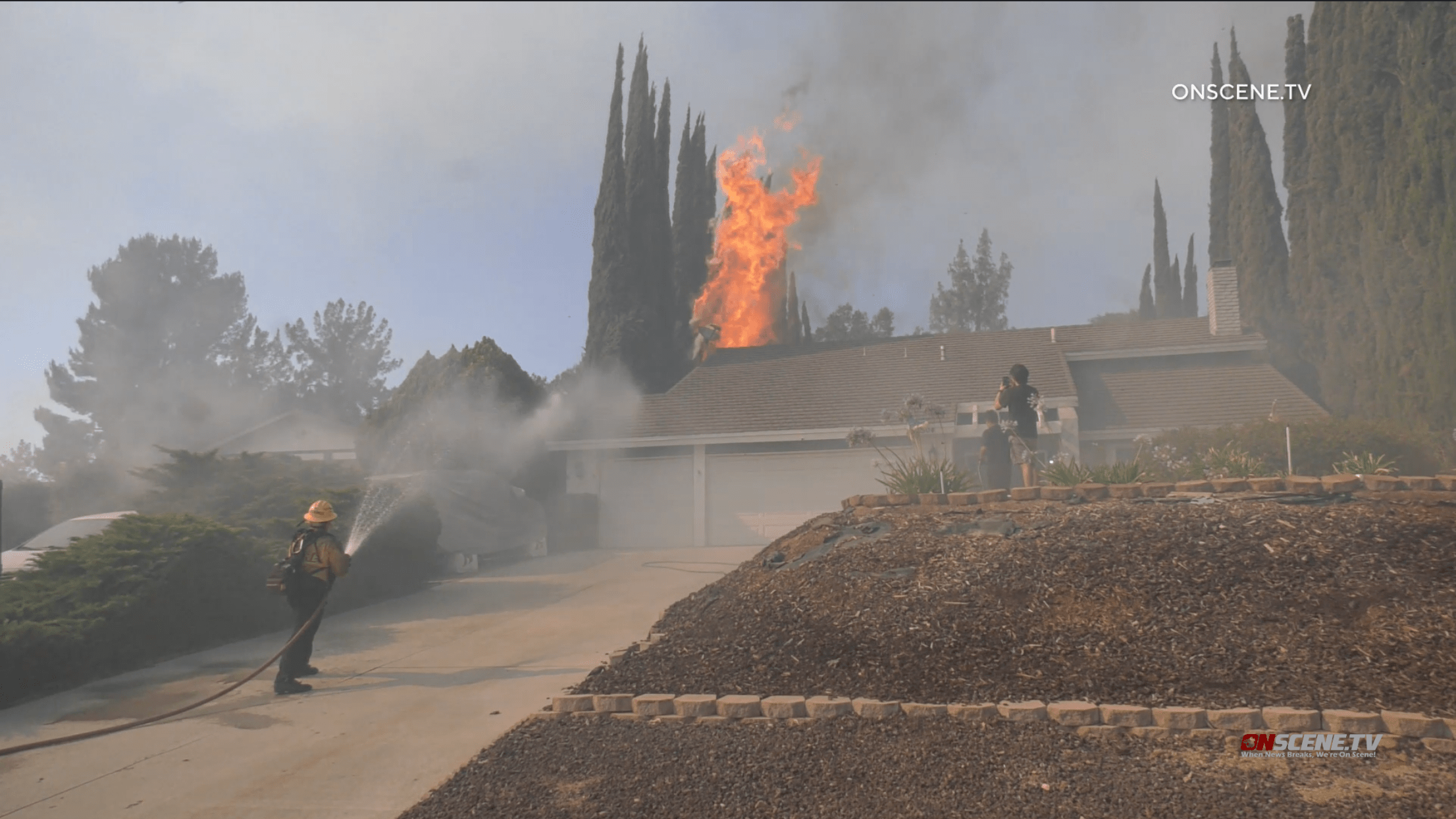 Flames burn dangeously close to a home in Jurupa Valley on Saturday, June 25, 2022 (OnScene.TV)