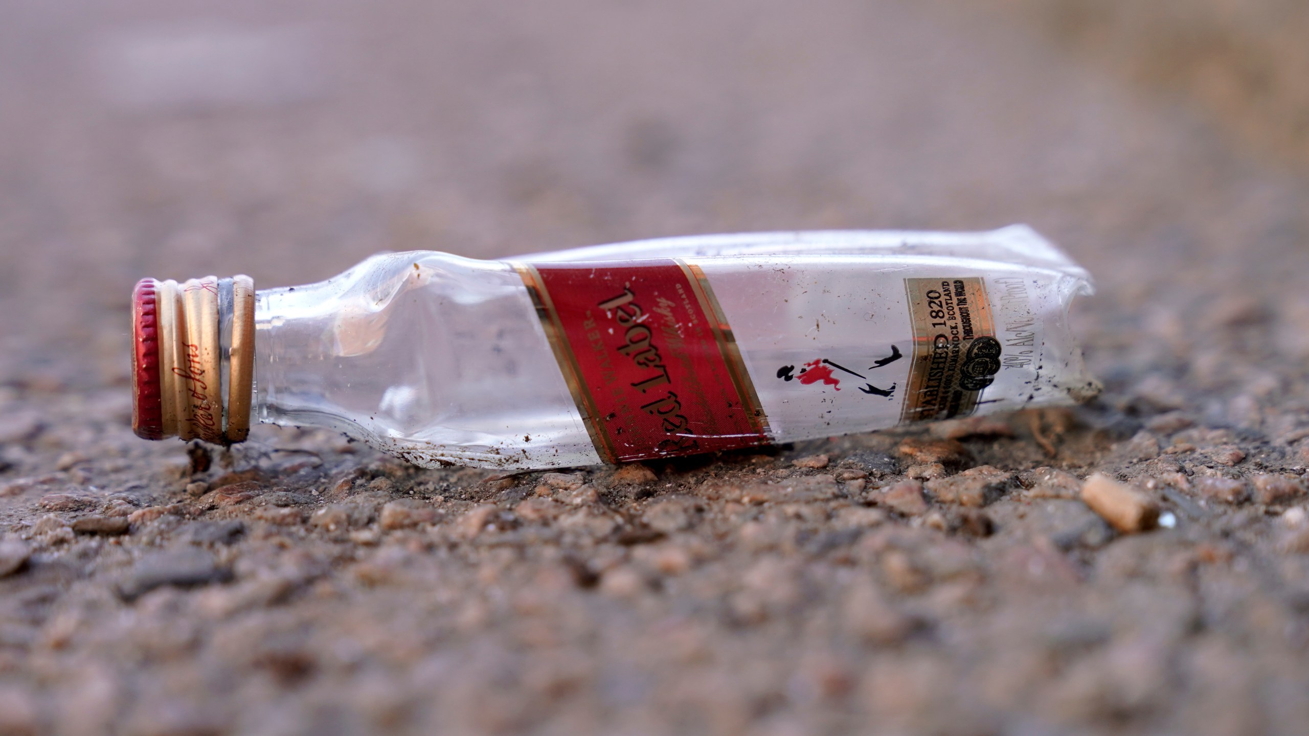 An empty miniature bottle that once contained liquor rests on a street near a sidewalk, Monday, April 3, 2023, in Boston. A Boston city councilor has proposed barring city liquor stores from selling the single-serve bottles that hold 100 milliliters or less of booze both as a way to address alcohol abuse and excessive litter. (AP Photo/Steven Senne)