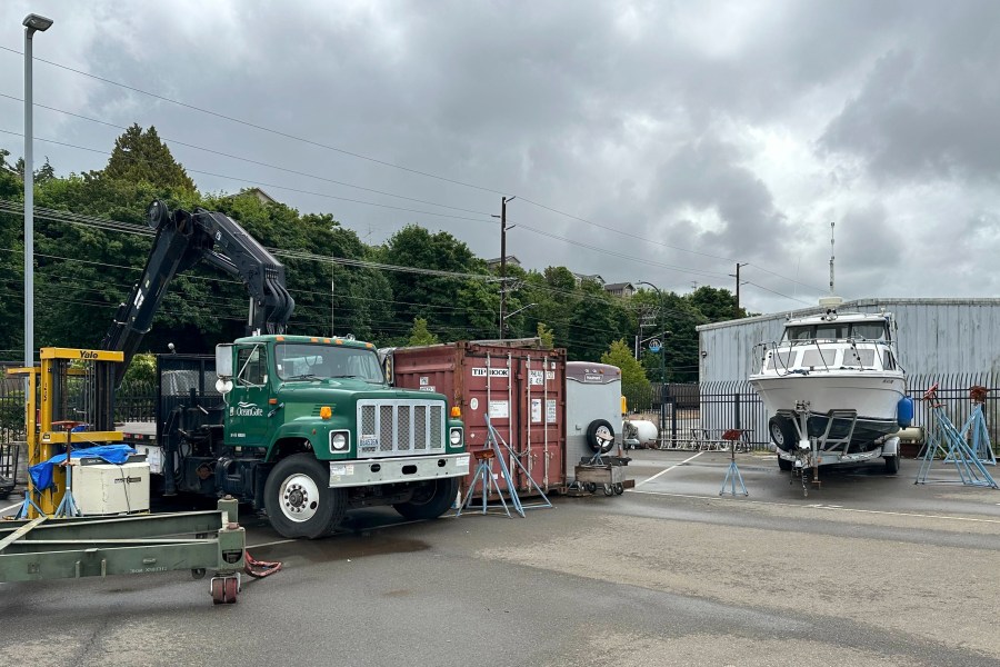 A crane truck and a boat with OceanGate logos are parked near the offices of the company in Everett, Wash., Tuesday, June 20, 2023. Rescuers are racing against time to find the missing submersible carrying five people, who were reported overdue Sunday night. (AP Photo/Ed Komenda)