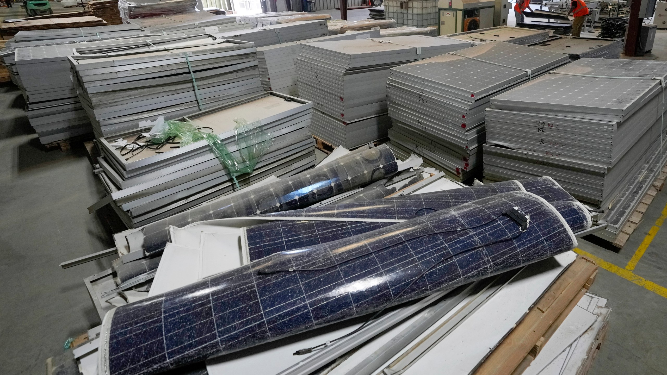 Workers take apart solar panels as they begin the recycling process at We Recycle Solar on Tuesday, June 6, 2023, in Yuma, Ariz. North America’s first utility-scale solar panel recycling plant opened to address what founders of the company call a “tsunami” of solar waste, as technology that became popular in the early 2000s rapidly scales up. (AP Photo/Gregory Bull)