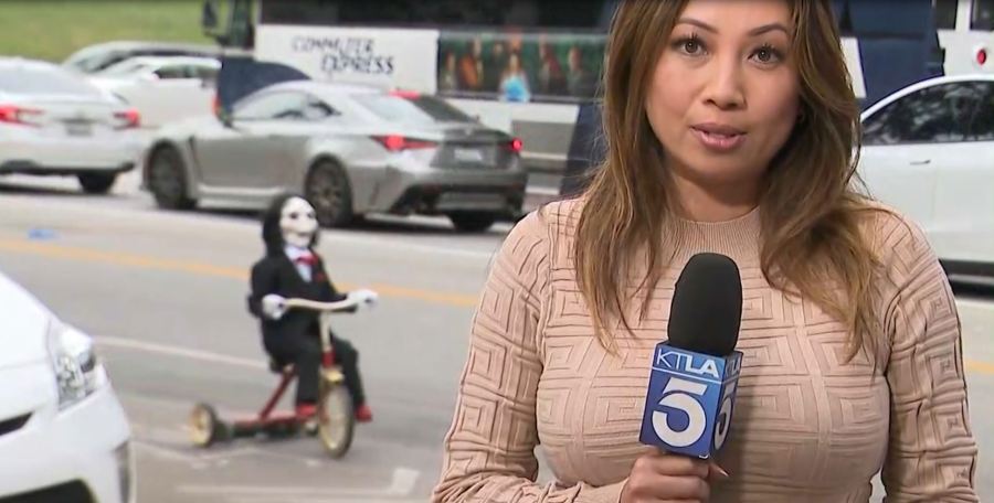 Billy the Puppet from the "Saw" horror film franchise videobombs KTLA's Kimberley Cheng in Westwood on Sept. 22, 2023. (KTLA)