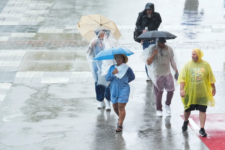 Fans walk in the rain during a thunderstorm delay before the start of the Indianapolis 500 auto race at Indianapolis Motor Speedway in Indianapolis, Sunday, May 26, 2024. (AP Photo/AJ Mast)