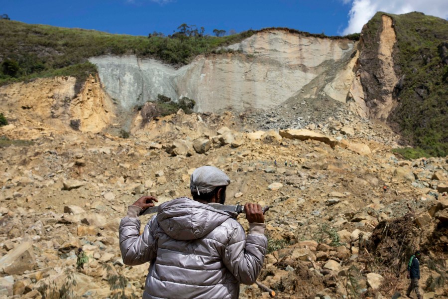 In this photo released by UNDP Papua New Guinea, a villager looks up at a landslide in Yambali village, in the Highlands of Papua New Guinea, Monday, May 27, 2024. Authorities fear a second landslide and a disease outbreak are looming at the scene of Papua New Guinea's recent mass-casualty disaster because of water streams trapped beneath tons of debris and decaying corpses seeping downhill following the May 24 landslide. (Juho Valta/UNDP Papua New Guinea via AP)