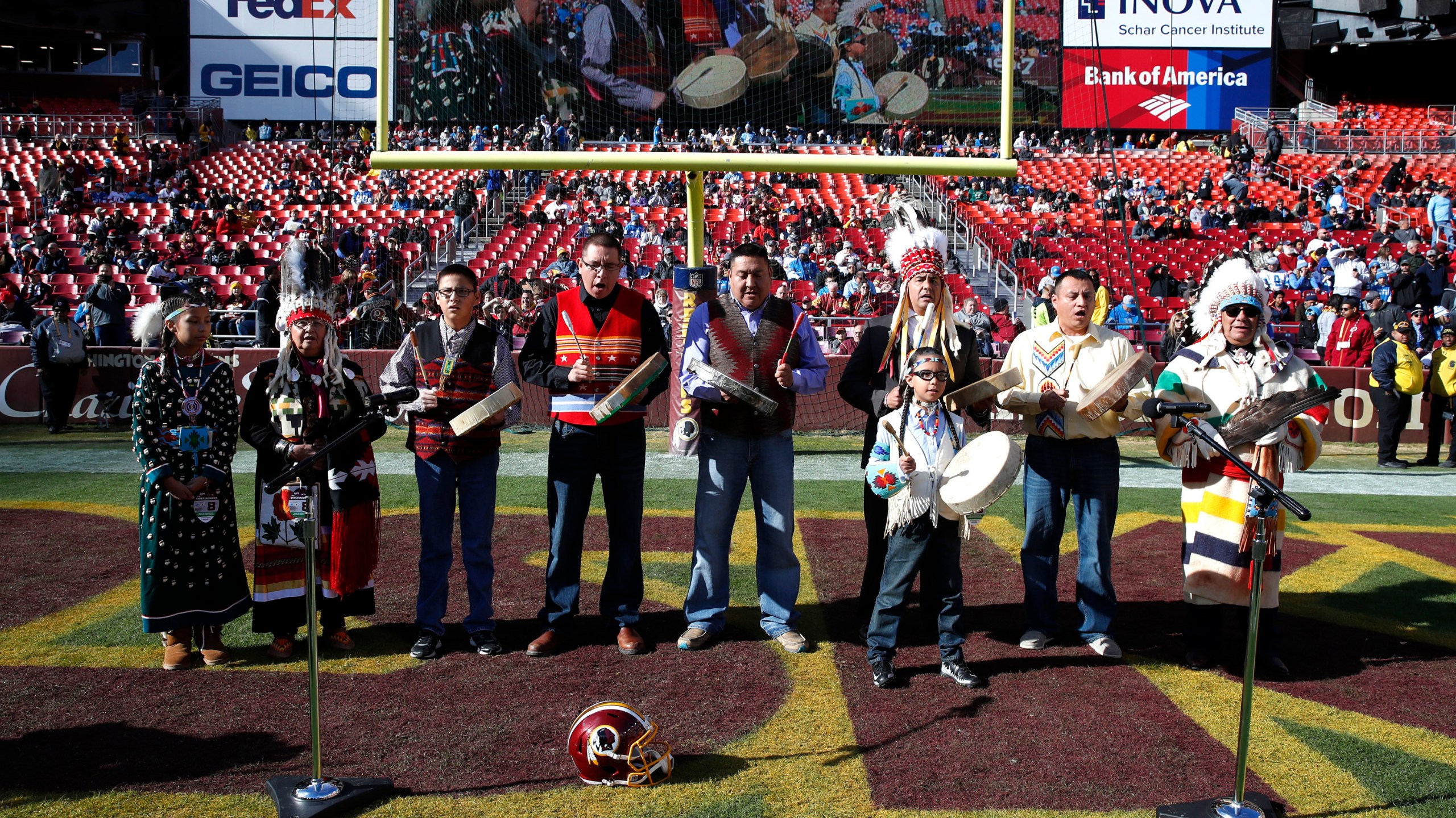 FILE - Members of the Blackfeet Nation perform as part of the Washington football team's observance of Native American Heritage Month prior to an NFL football game on Nov. 24, 2019, in Landover, Md. Many Native Americans thought a bitter debate over the U.S. capital’s football mascot was over when the team became the Washington Commanders. The original logo was designed by a member of the Blackfeet Nation. Now a white Republican U.S. senator from Montana is reviving the debate by blocking a bill funding the revitalization of the team's stadium unless the NFL and the Commanders bring back the former logo in some form. (AP Photo/Alex Brandon, File)