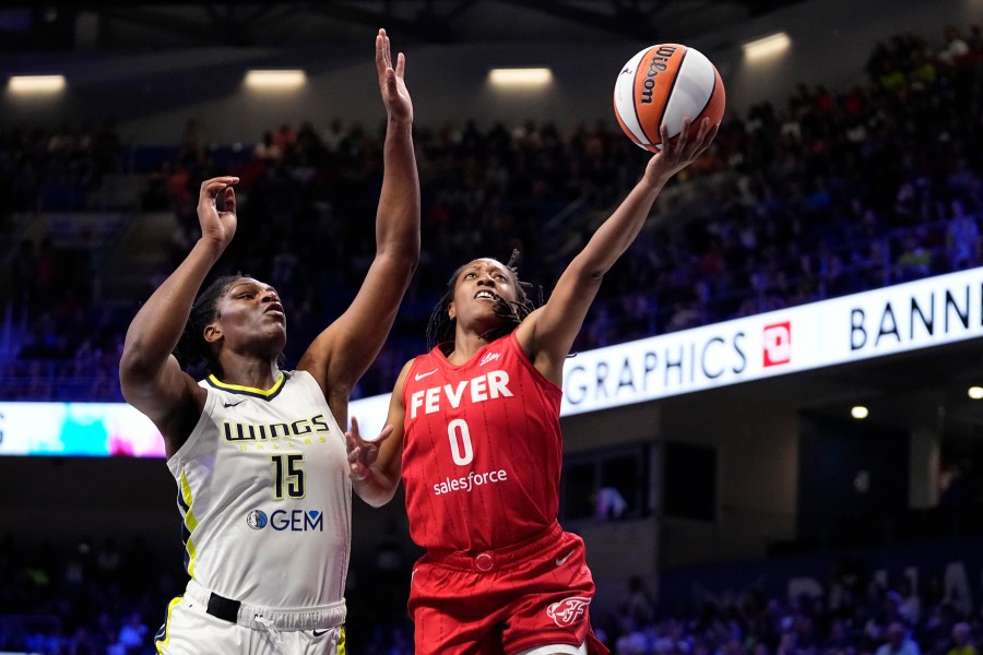 Indiana Fever's Kelsey Mitchell (0) leaps to the basket to take a shot as Dallas Wings' Teaira McCowan (15) defends in the first half of a WNBA basketball game Wednesday, July 17, 2024, in Arlington, Texas. (AP Photo/Tony Gutierrez)